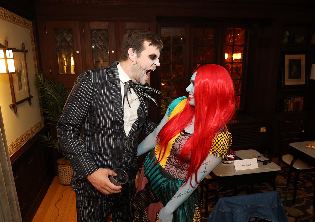 A man and woman in Halloween costumes laughing together indoors.