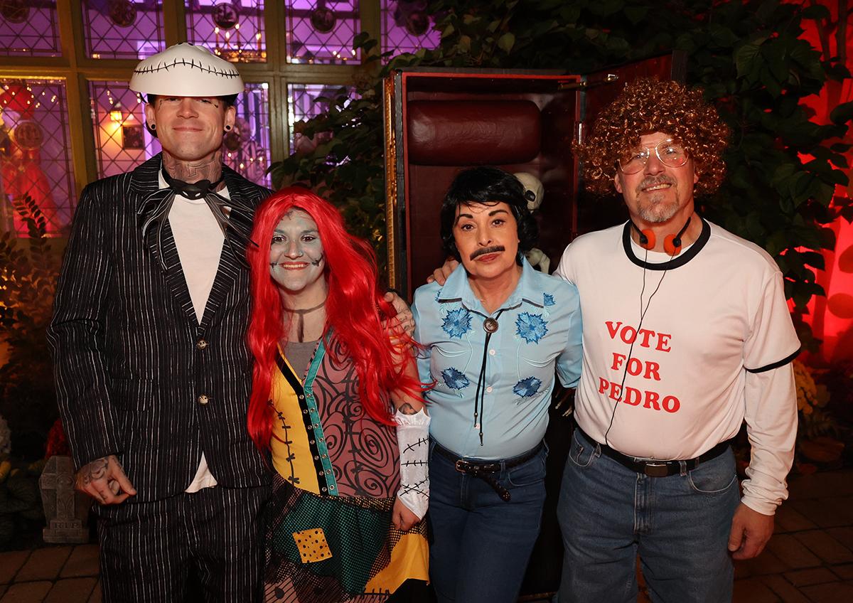 Group in various colorful costumes, standing in a festively lit room.