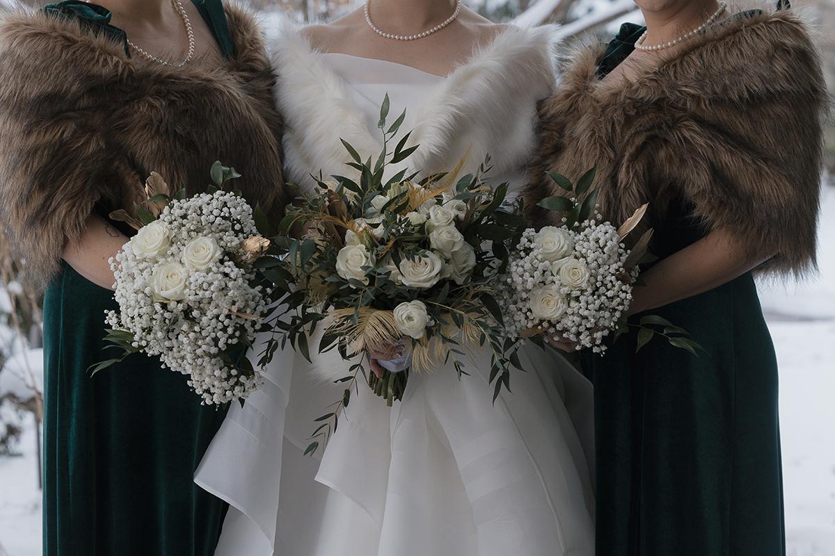 Bride and bridesmaids in fur stoles holding white bouquets.