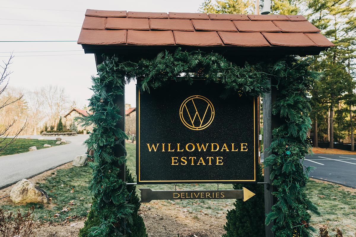 Willowdale Estate sign with greenery and pathway on a clear day.