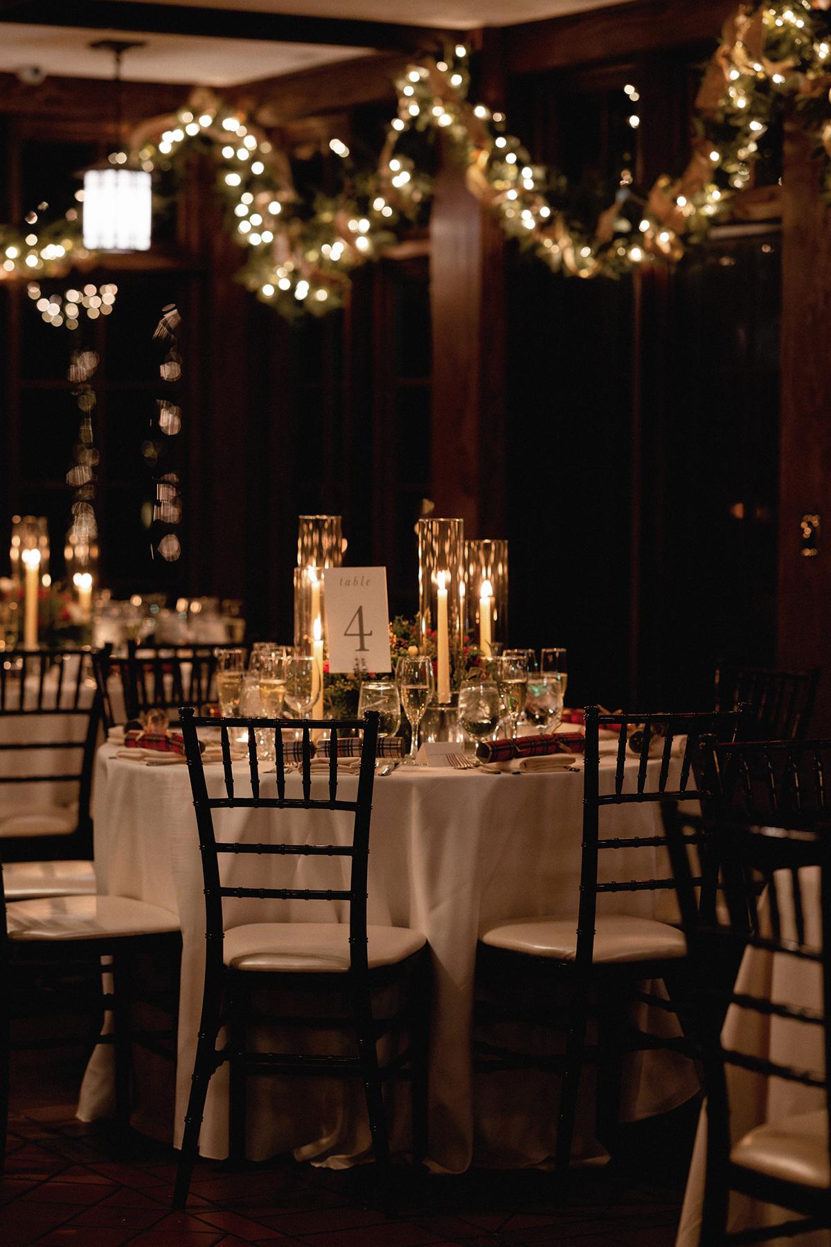 Elegant candlelit dining table with festive garland and dim lighting.