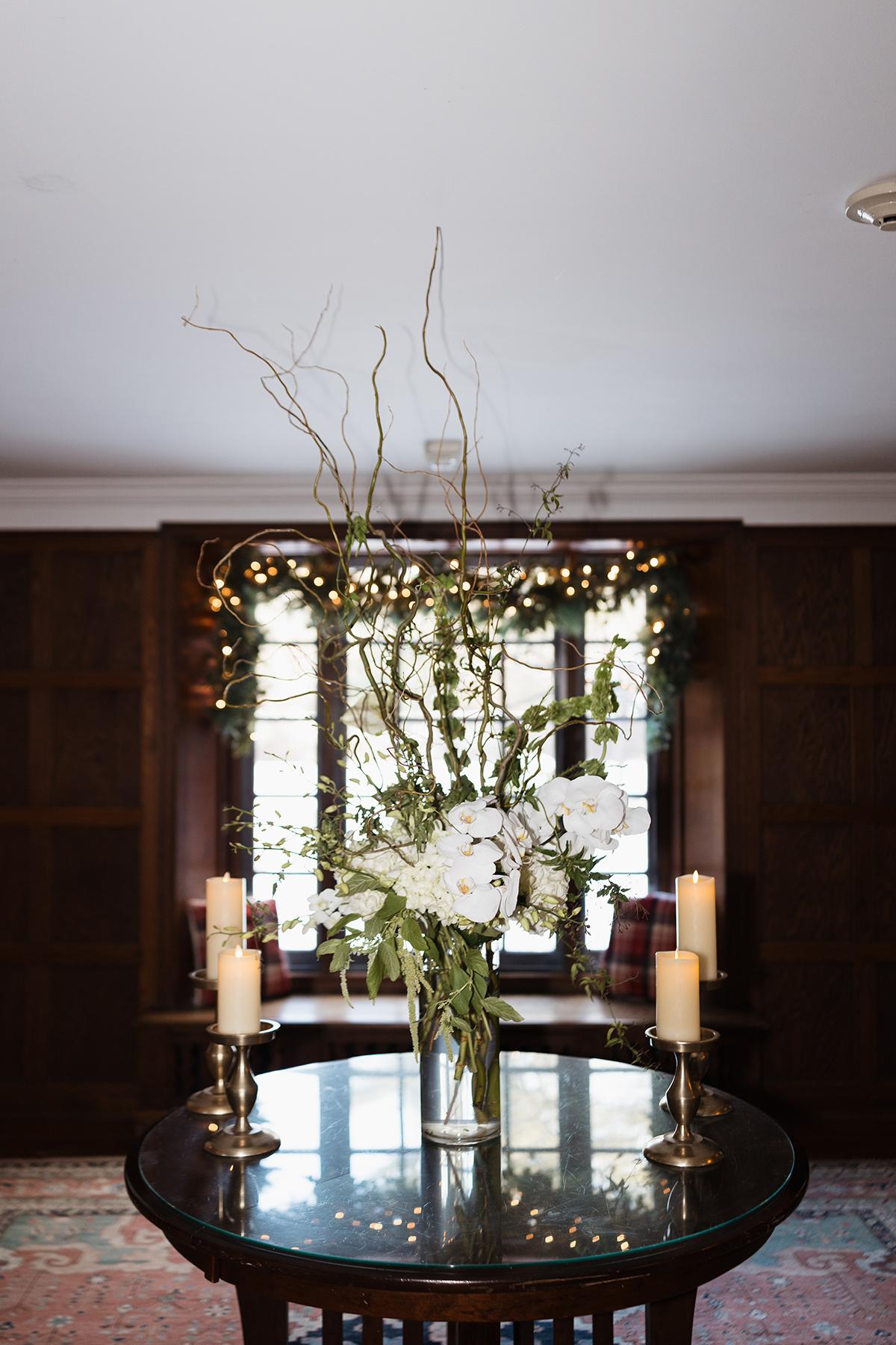 Elegant floral centerpiece with candles on a wooden table.