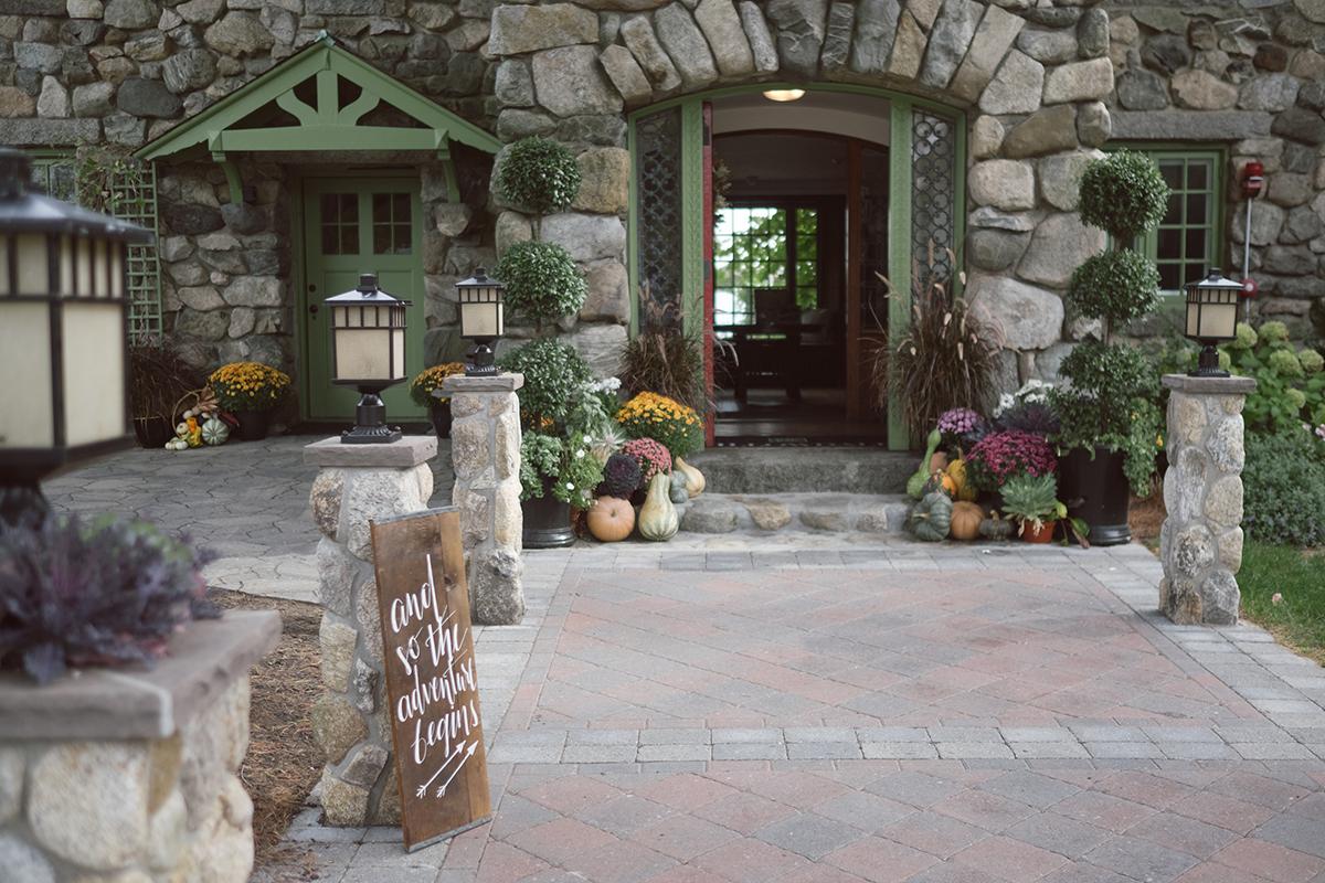 Stone building entrance with fall decor and plants.