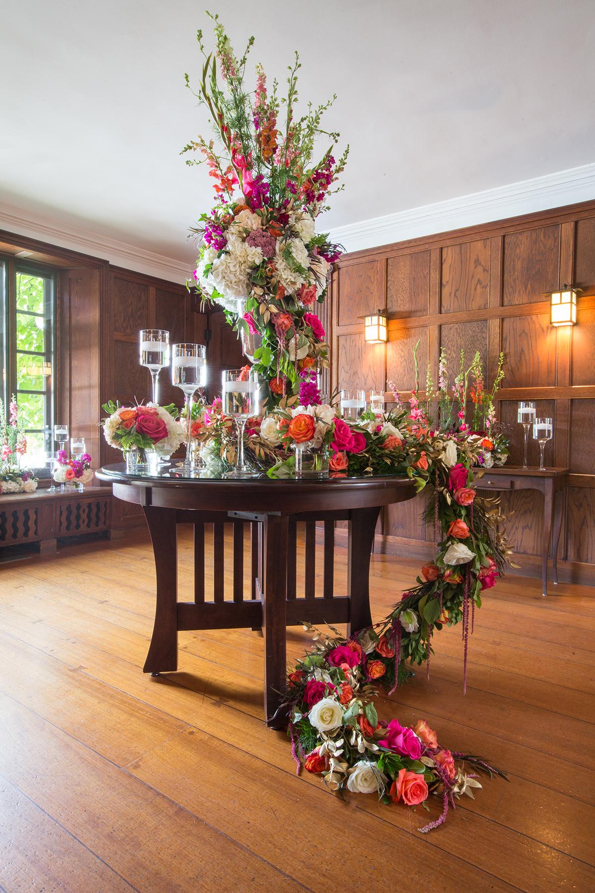 Floral arrangement on wooden table in elegant room with candles.