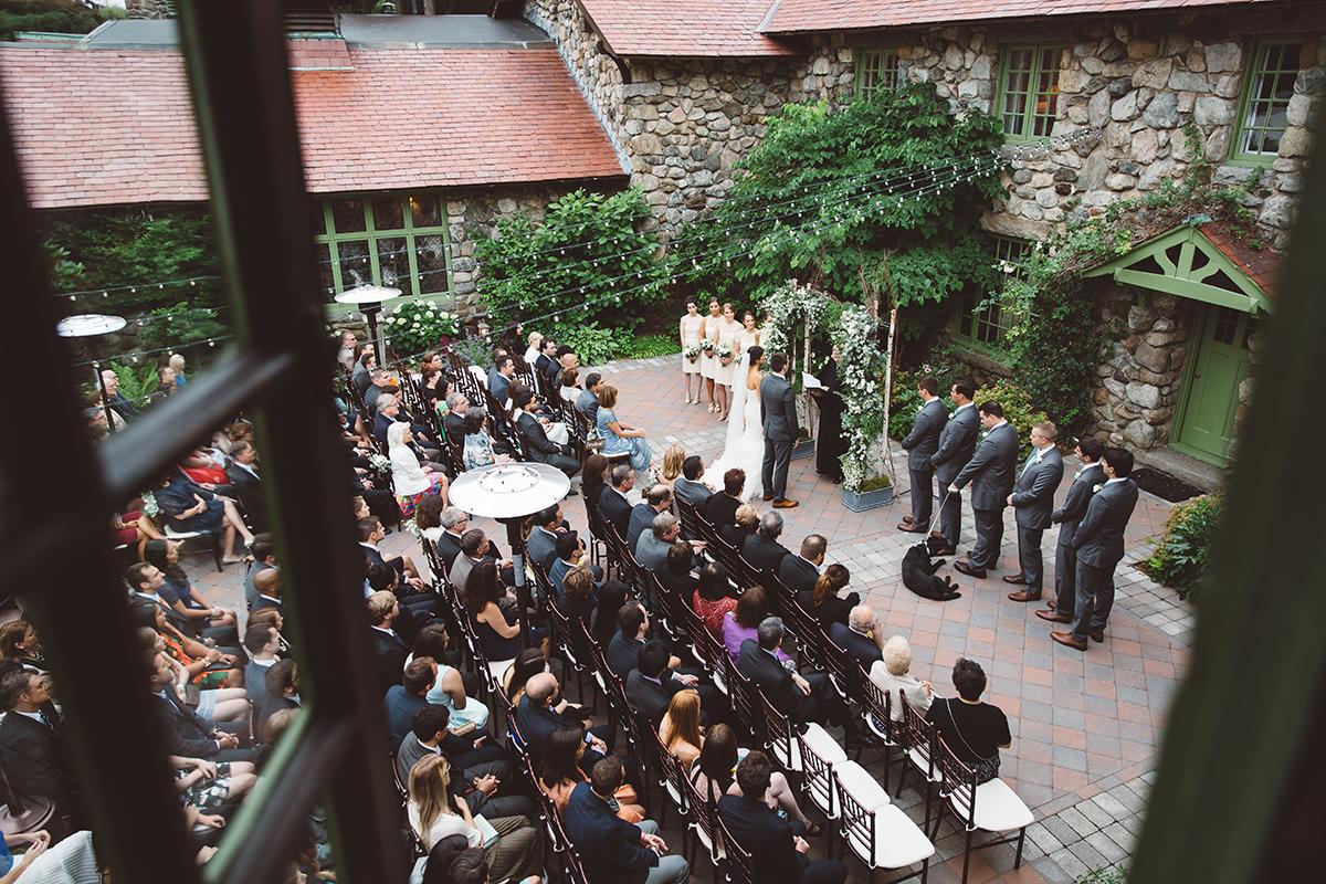 Outdoor wedding ceremony in a courtyard with guests seated.