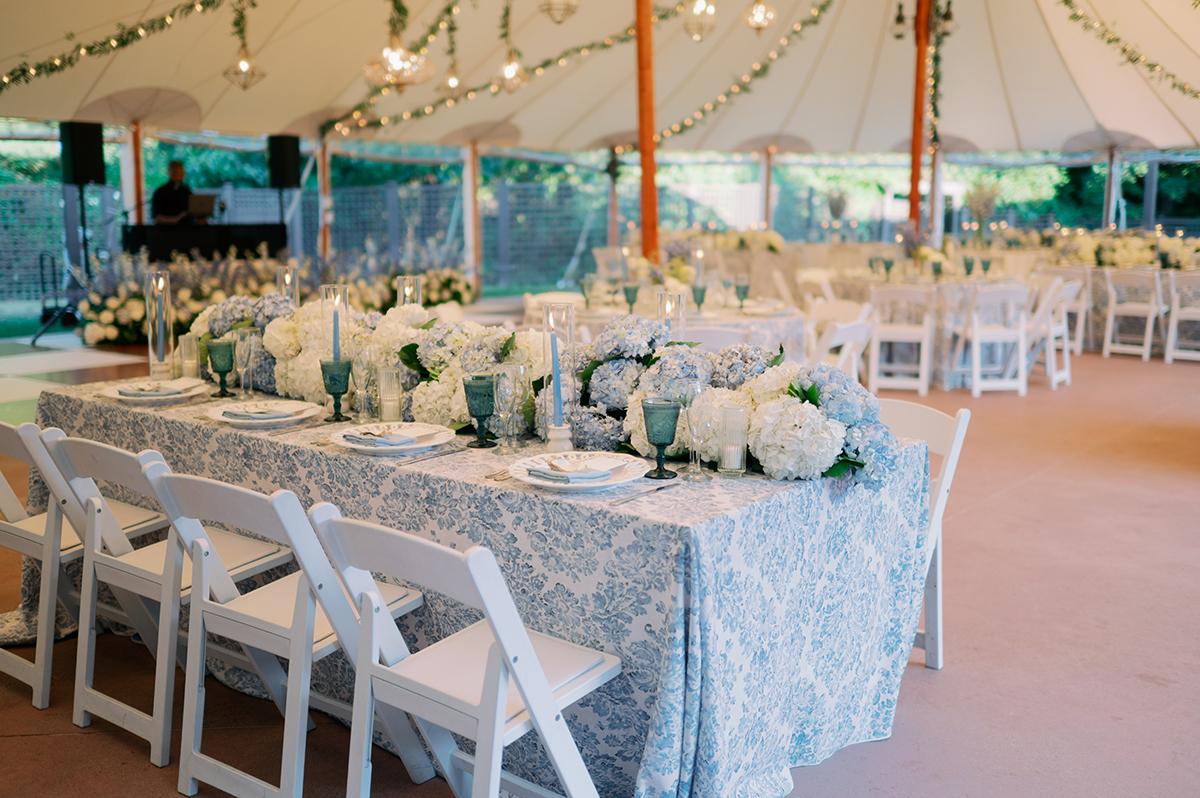 Elegant outdoor wedding reception with floral centerpieces and string lights.