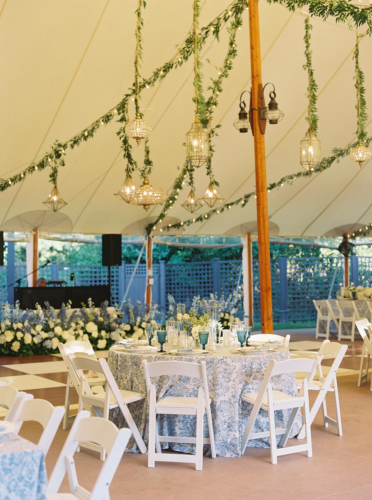 Elegant wedding reception with floral decorations under a white tent.