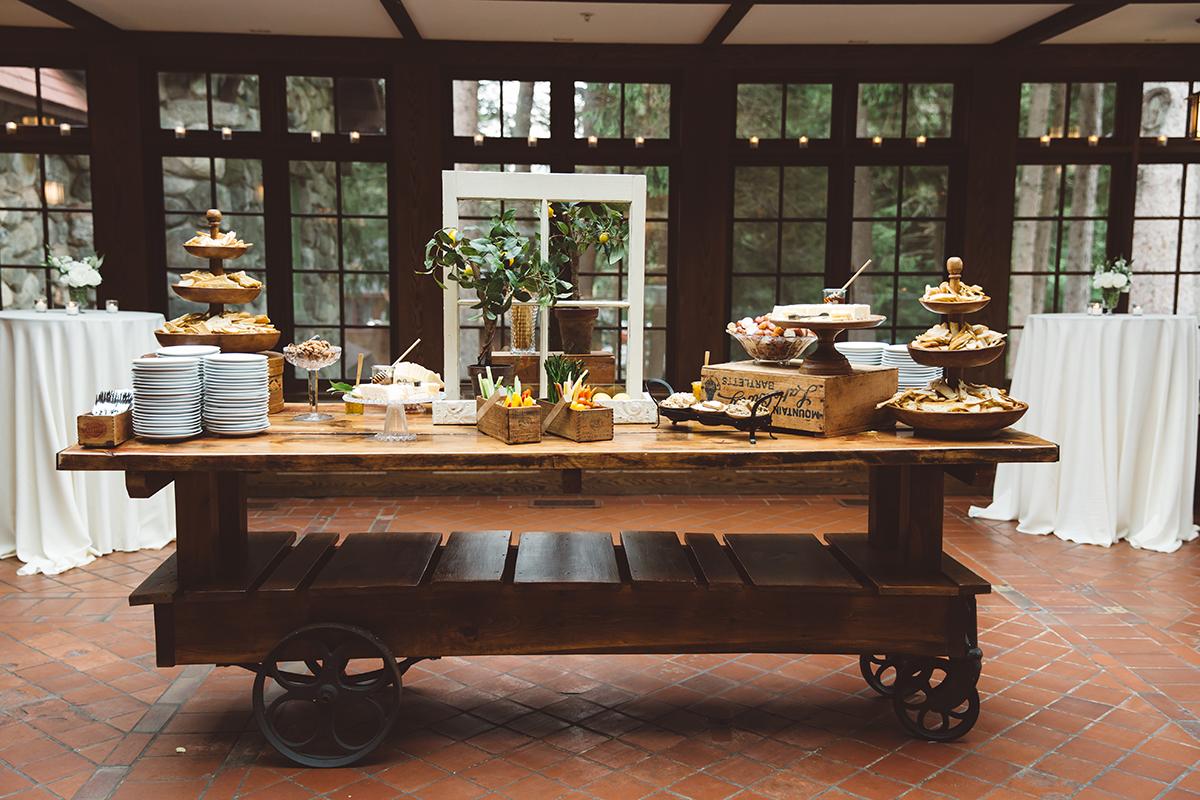 Rustic dessert table with pastries and fruit, set indoors with a garden view.