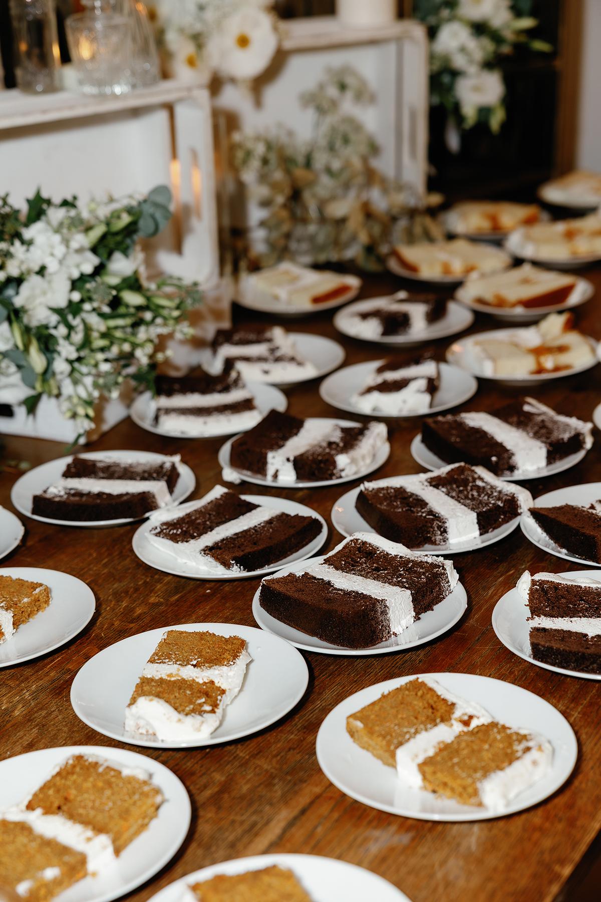 Plates of chocolate and vanilla cake slices on a wooden table.
