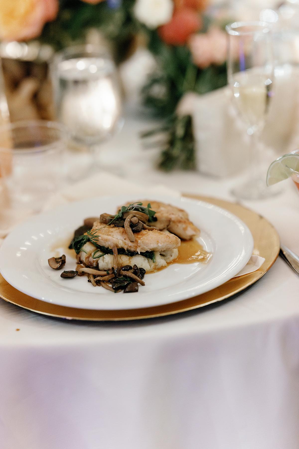 Seared chicken with mushrooms on a white plate, elegant table setting.