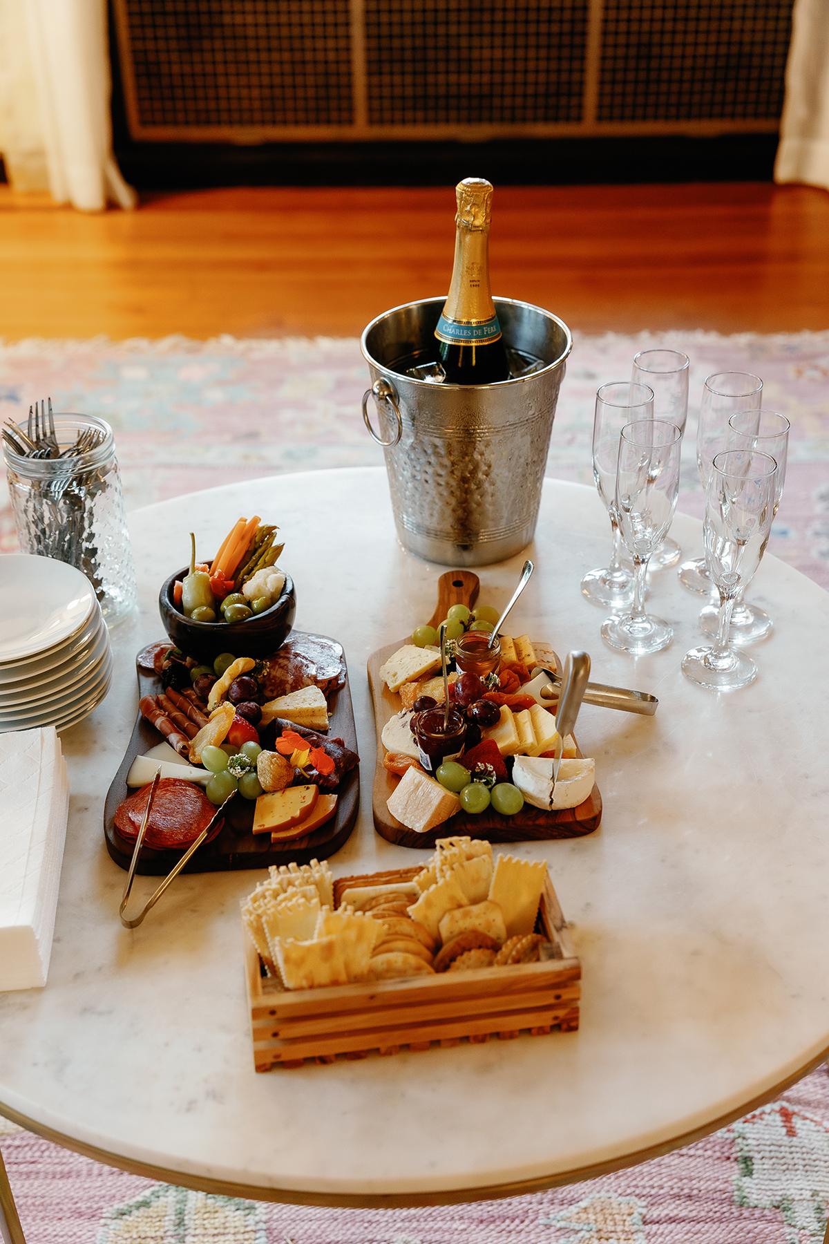 Cheese and fruit platter with champagne on a marble table.