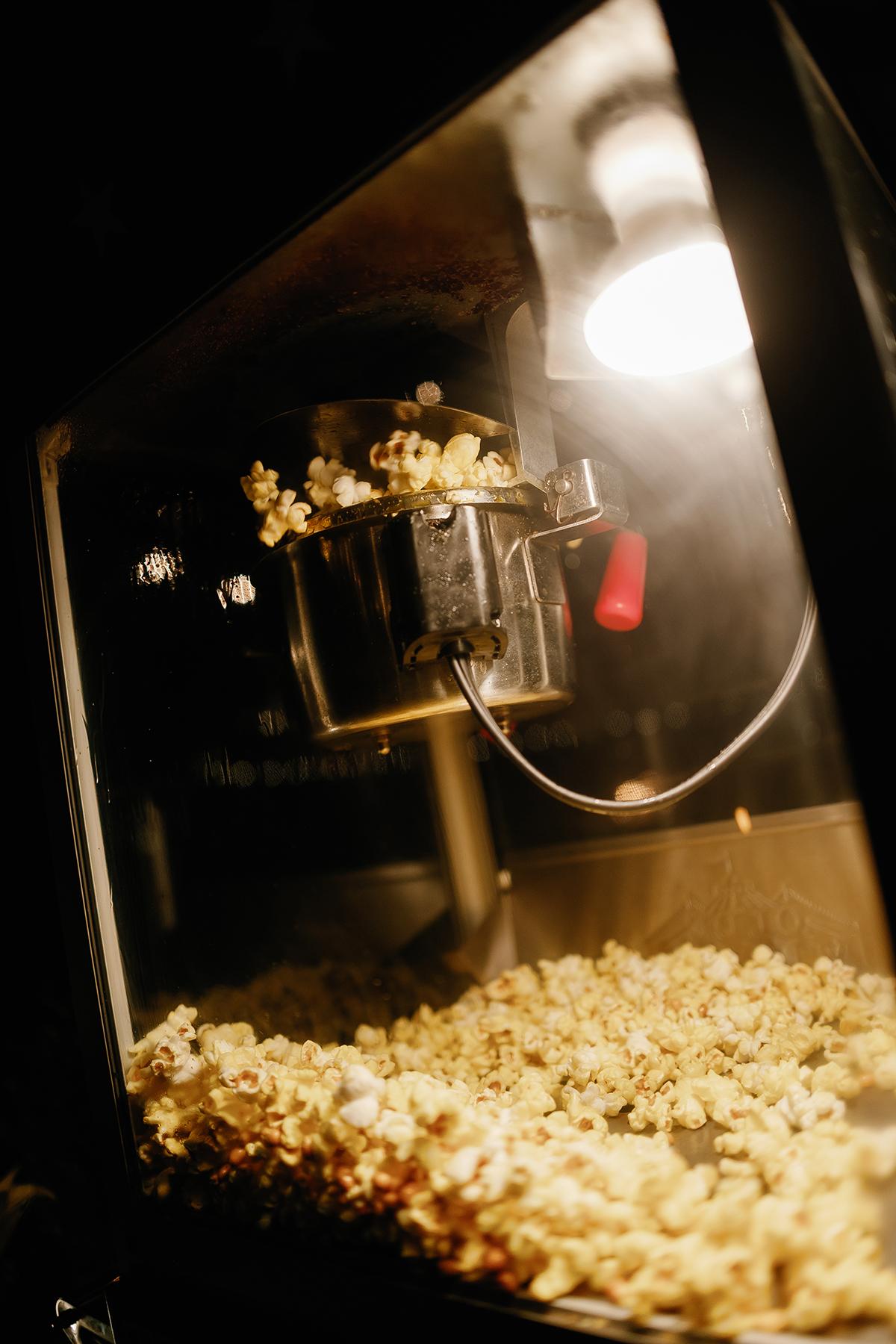 Popcorn machine with popping corn inside, warmly lit.