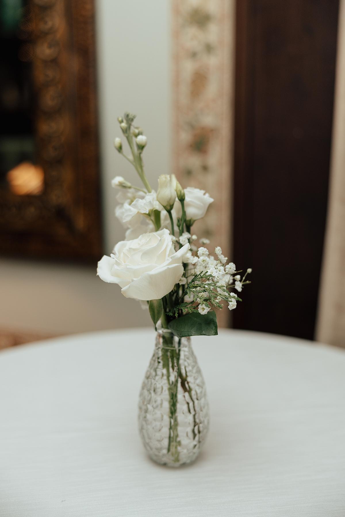 White flowers in a clear glass vase on a white table.