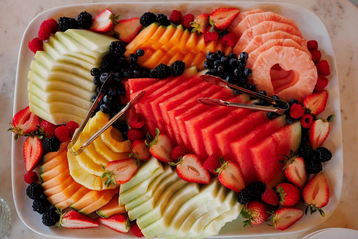 Colorful fruit platter with sliced melons, strawberries, and blueberries.