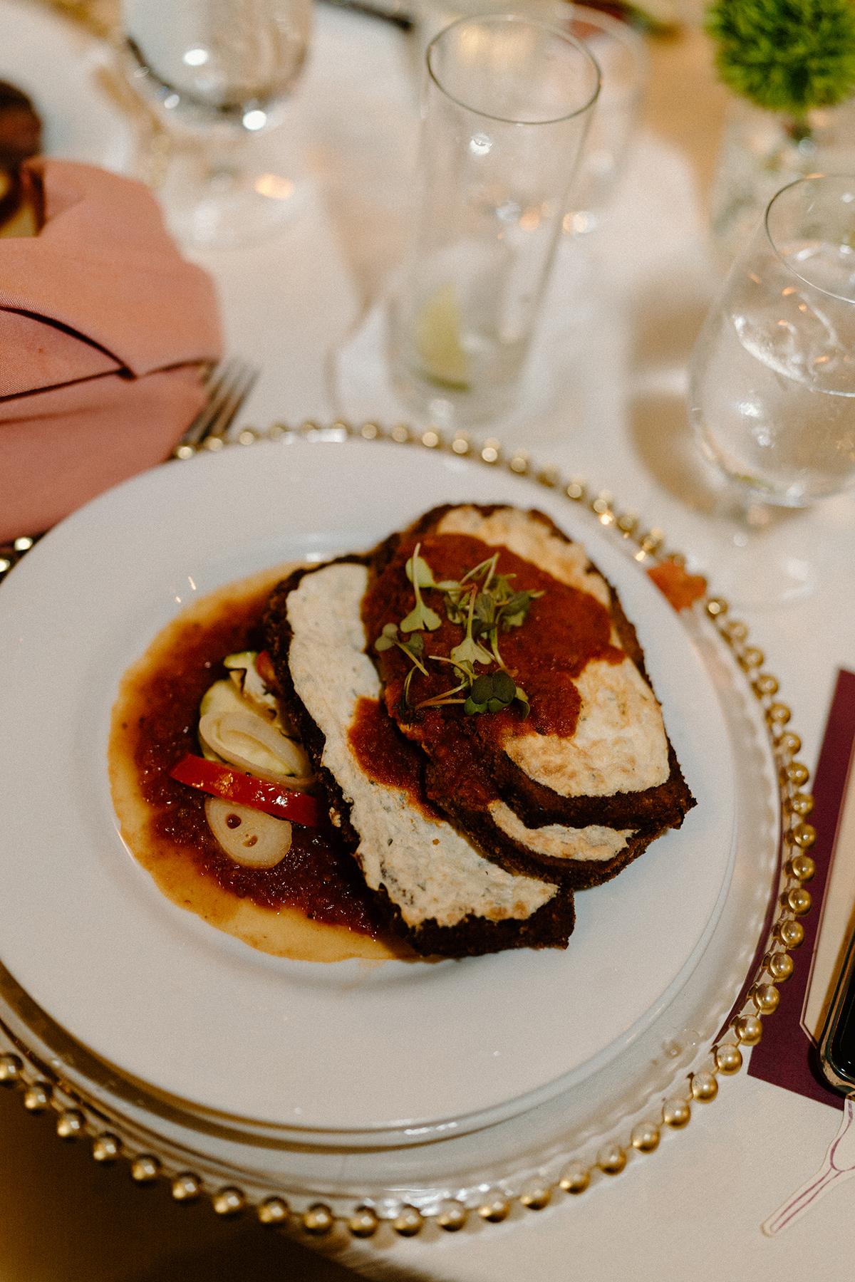 Two slices of roast beef with sauce on a white plate.