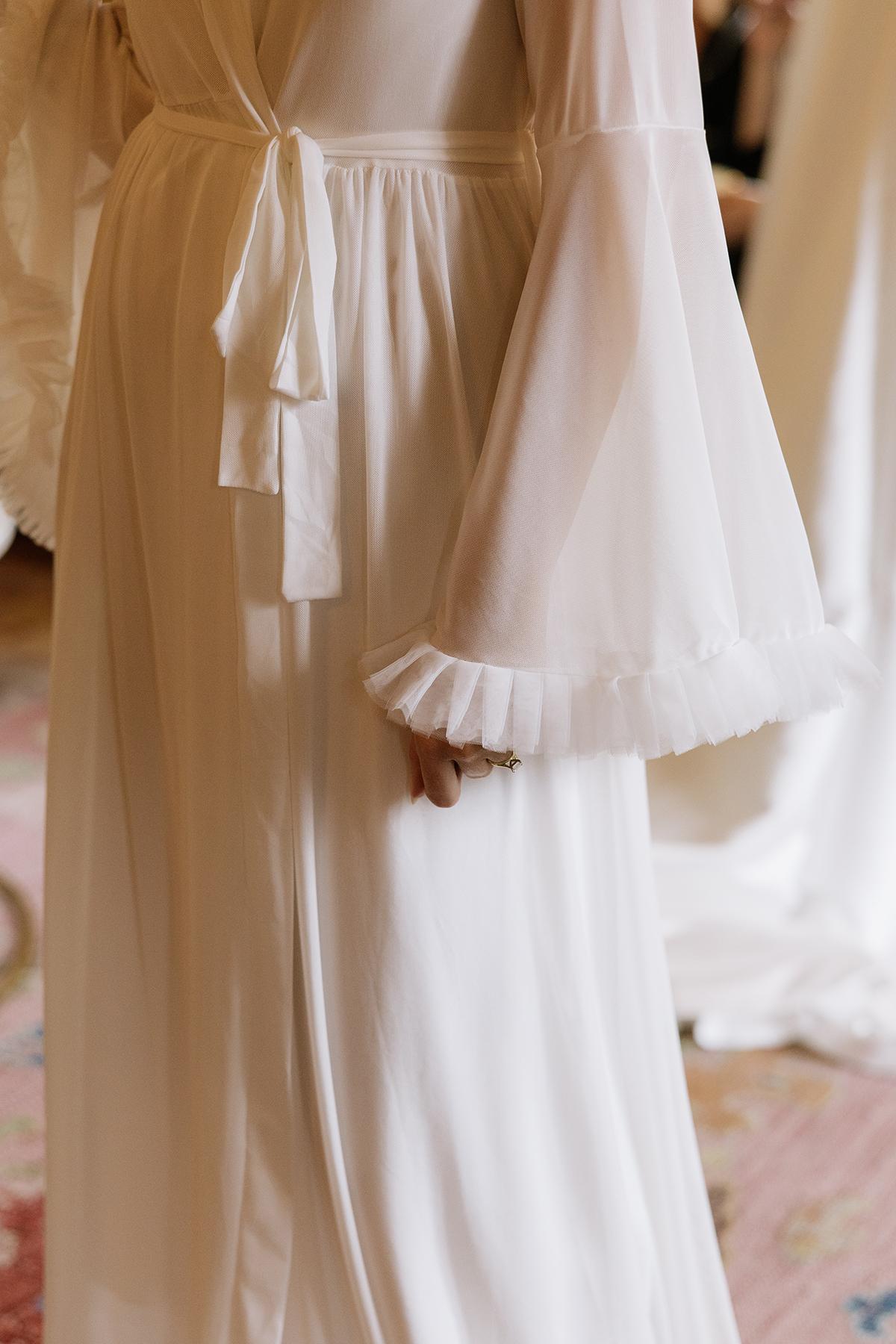 A person in a flowing white gown with sheer, ruffled sleeves.