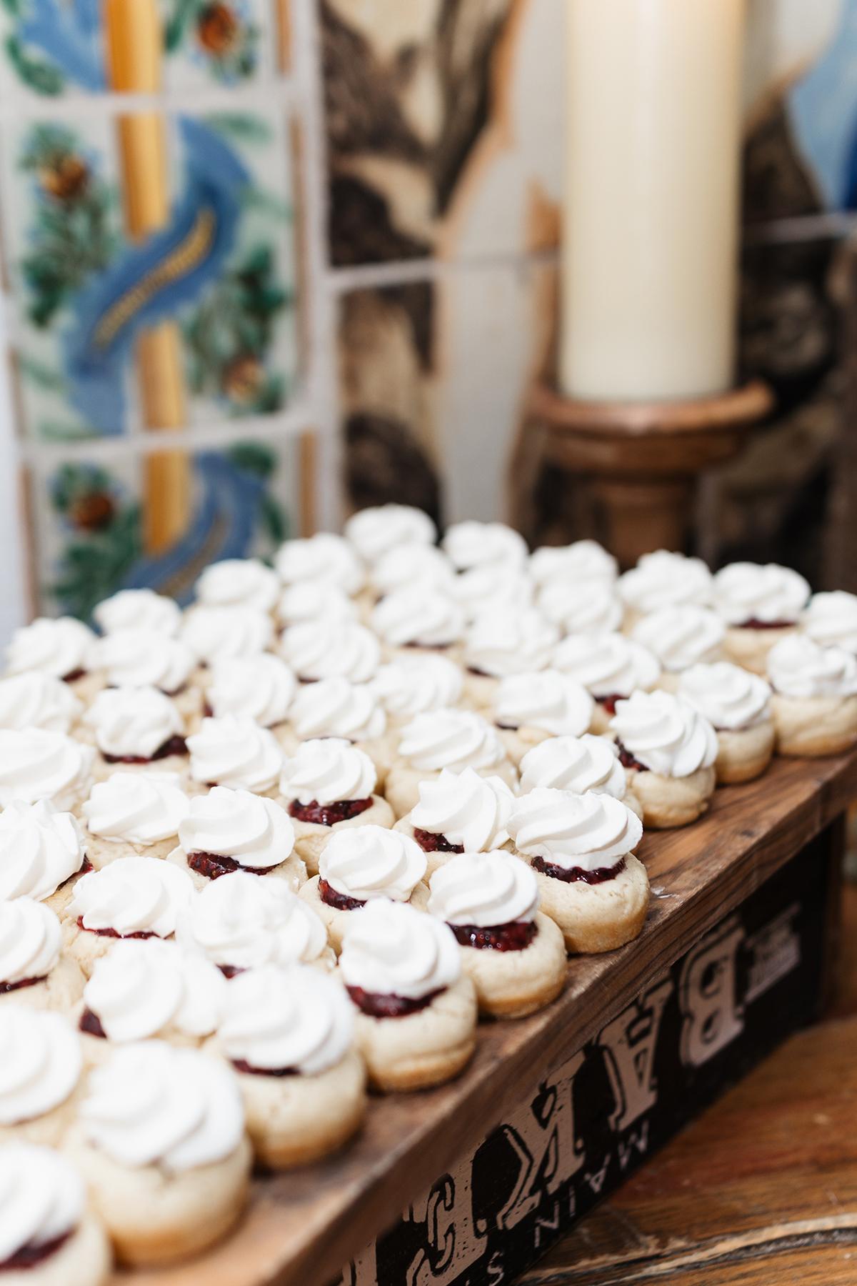 Mini cupcakes with white frosting on a wooden tray in a colorful tiled setting.