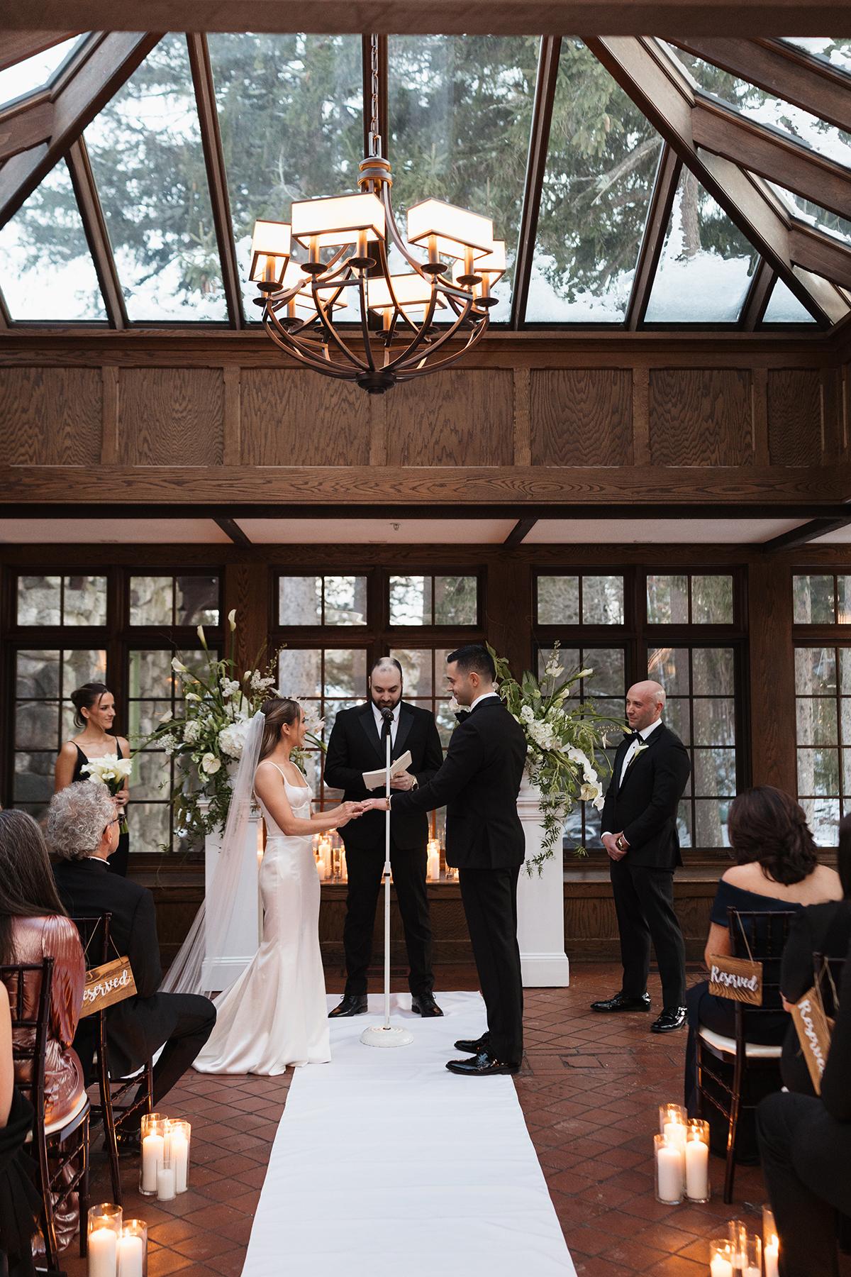 Bride and groom standing at altar in a sunlit conservatory wedding ceremony.