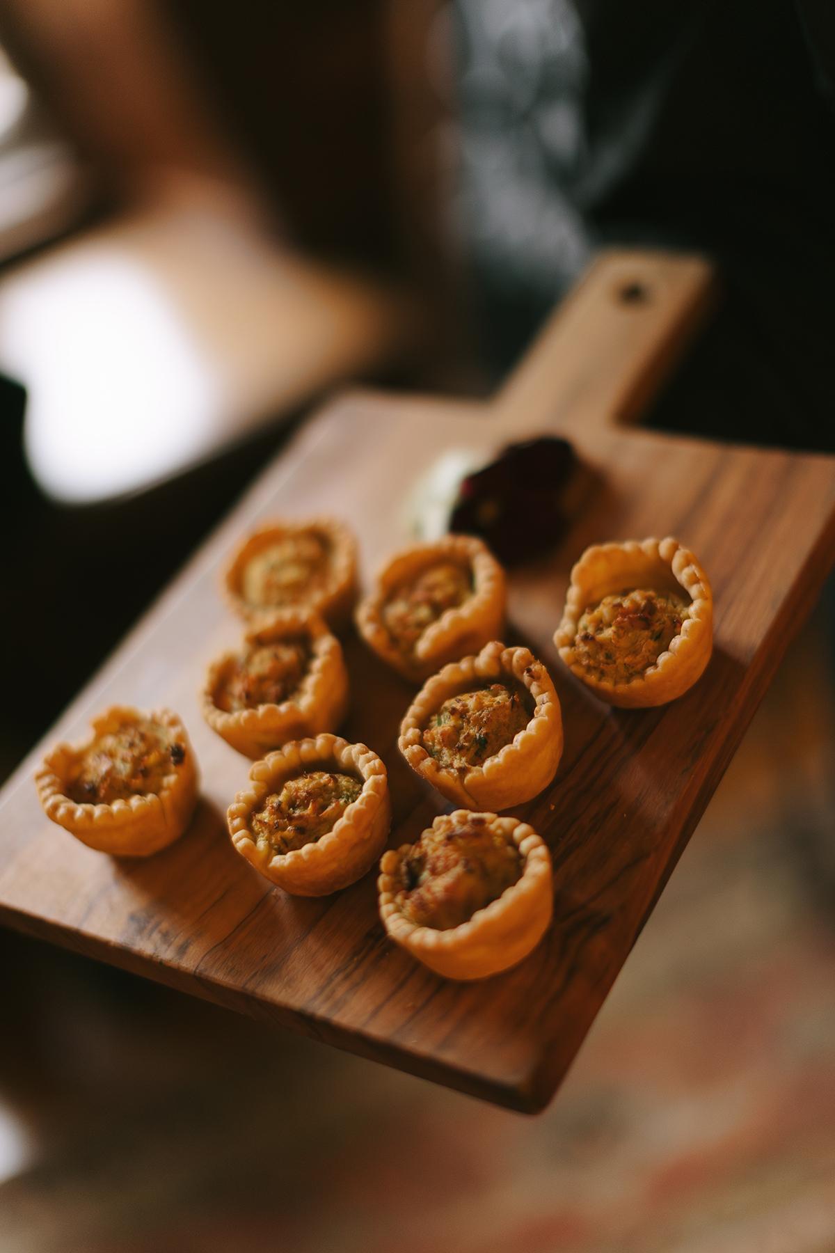 Savory pastries on a wooden board with a creamy dip.