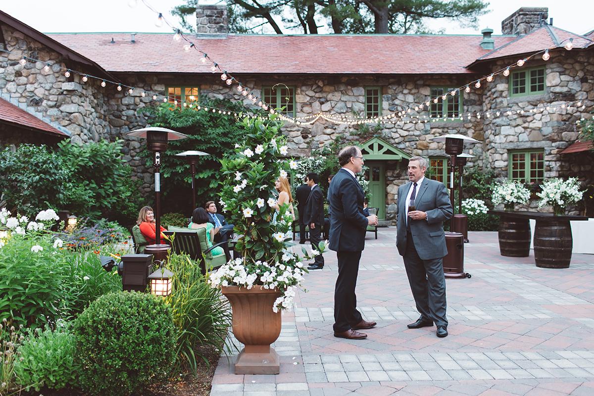 Courtyard gathering with two men in suits conversing.
