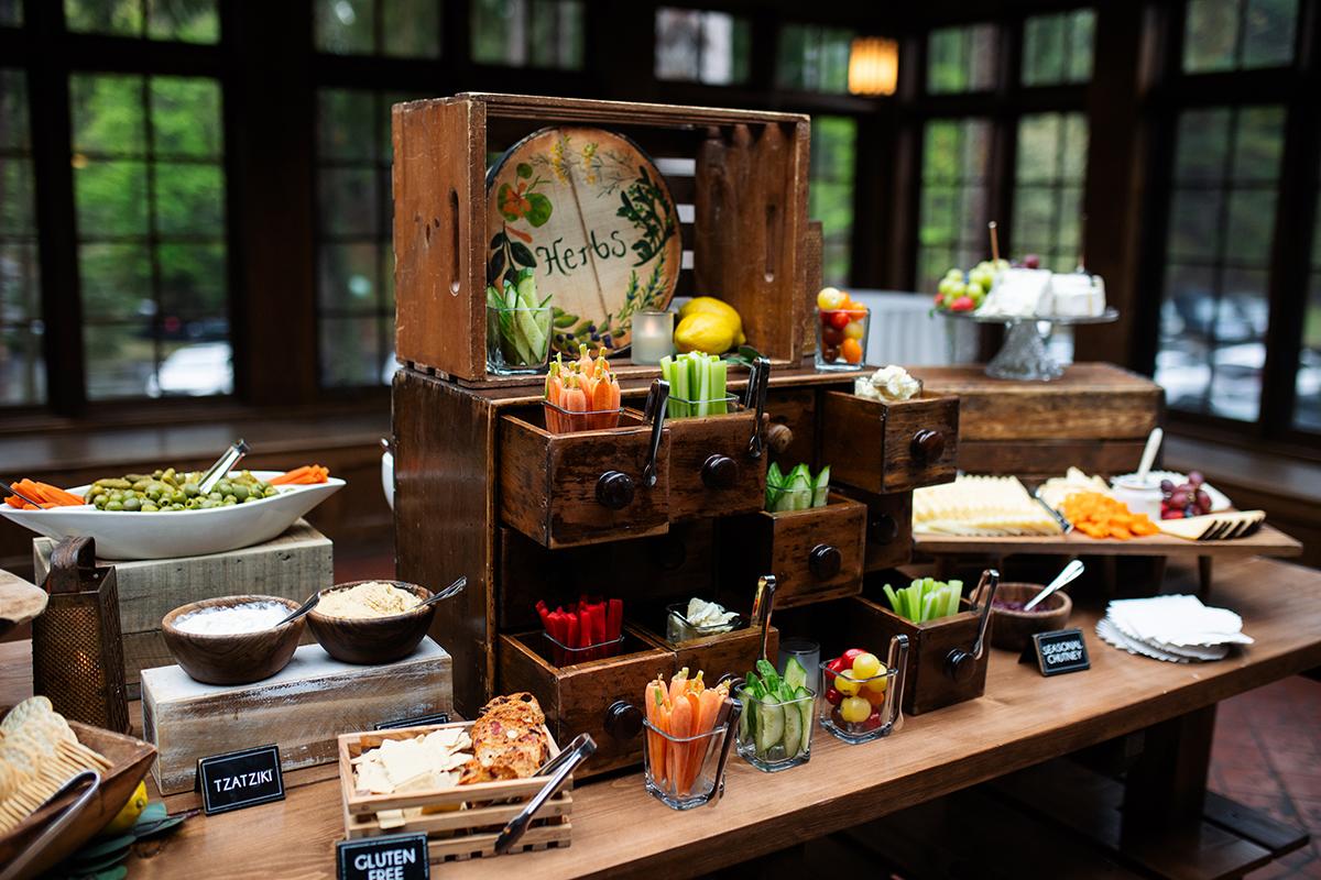 Buffet with wooden shelves, assorted vegetables, and dips on a table.