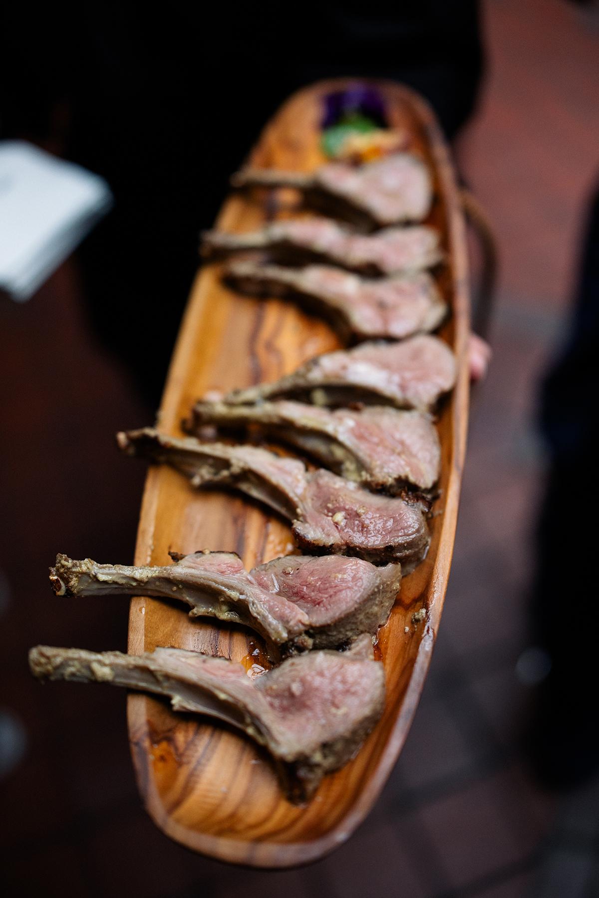 Grilled lamb chops arranged on a wooden serving platter.