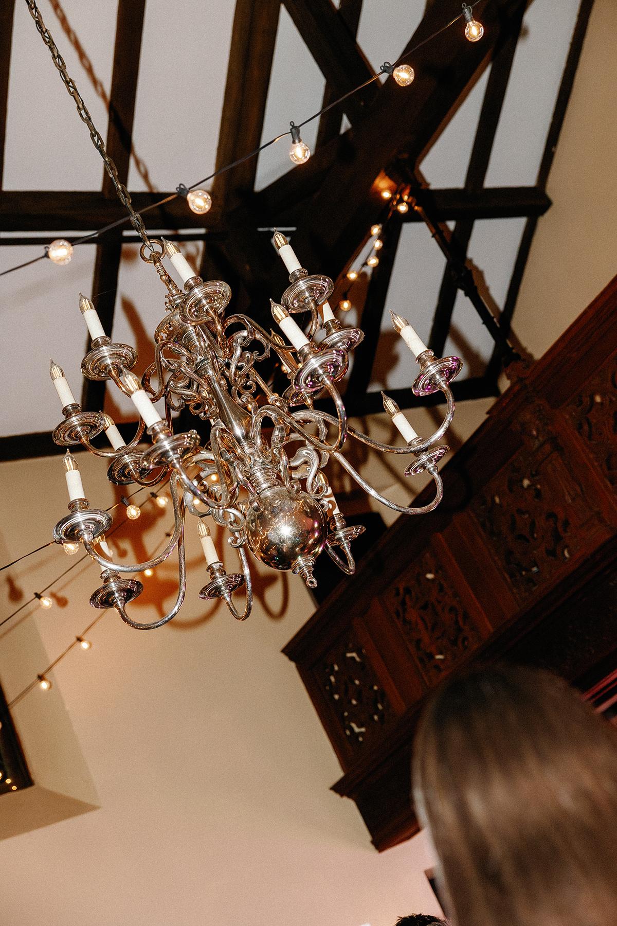 Elegant chandelier hanging from wooden ceiling with decorative beams.