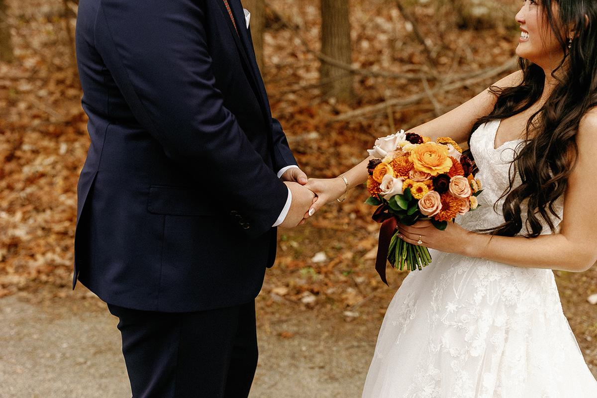Bride and groom holding hands, bride with colorful bouquet.