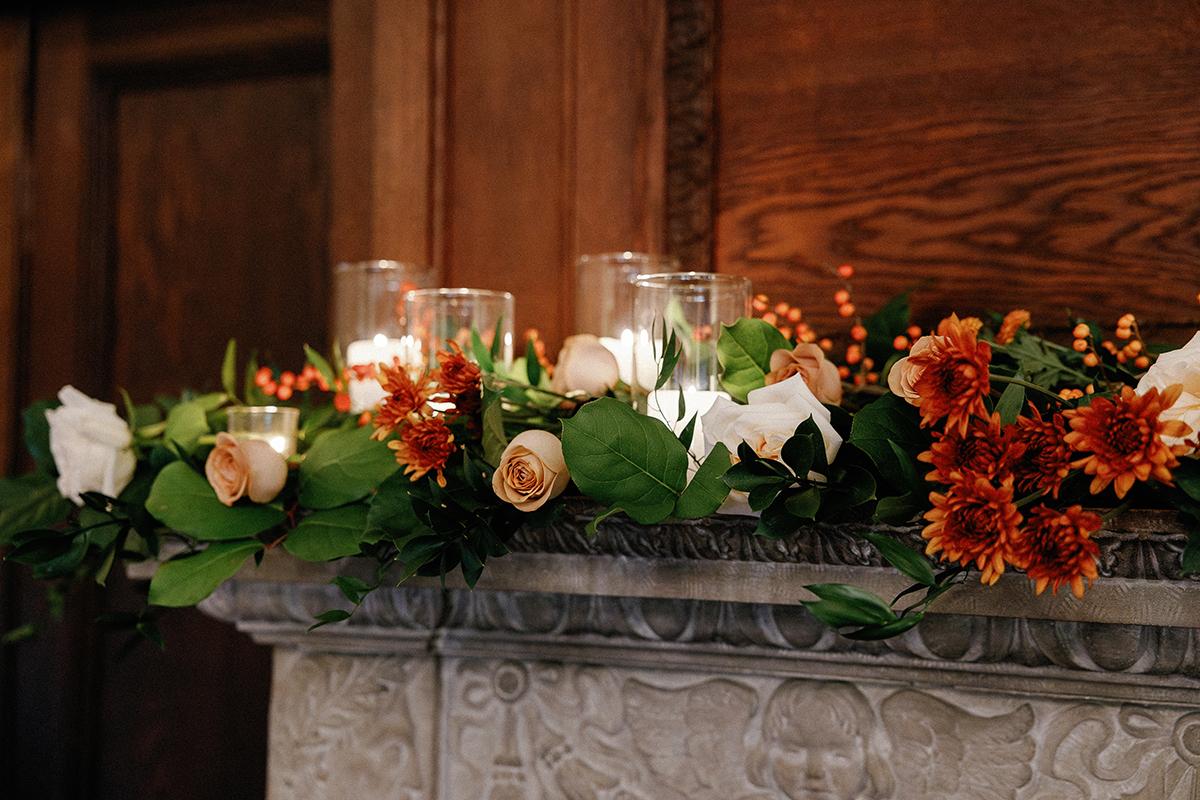 Candles and autumn flowers on a mantel, creating a warm ambiance.