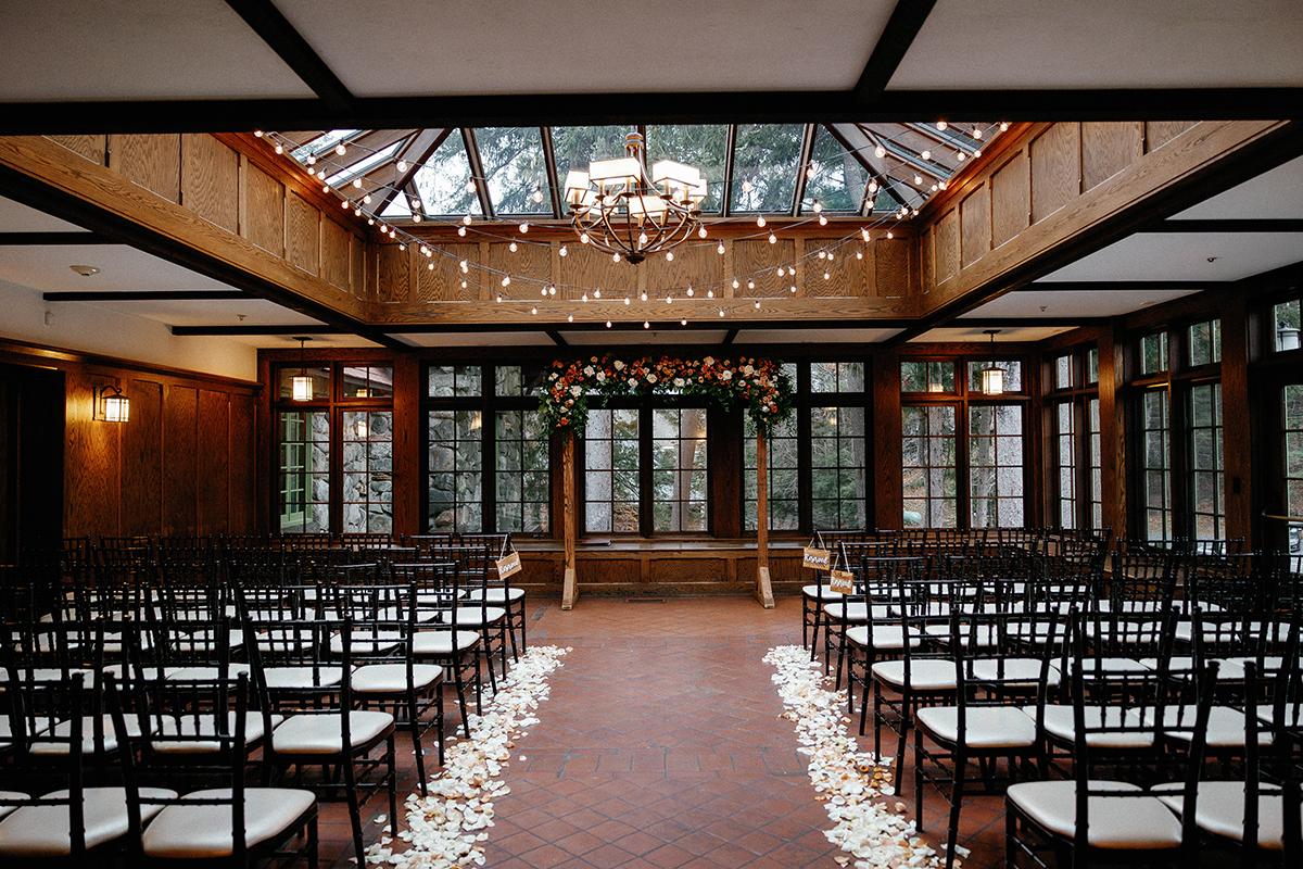 Elegant indoor wedding venue with rows of chairs and floral arch.