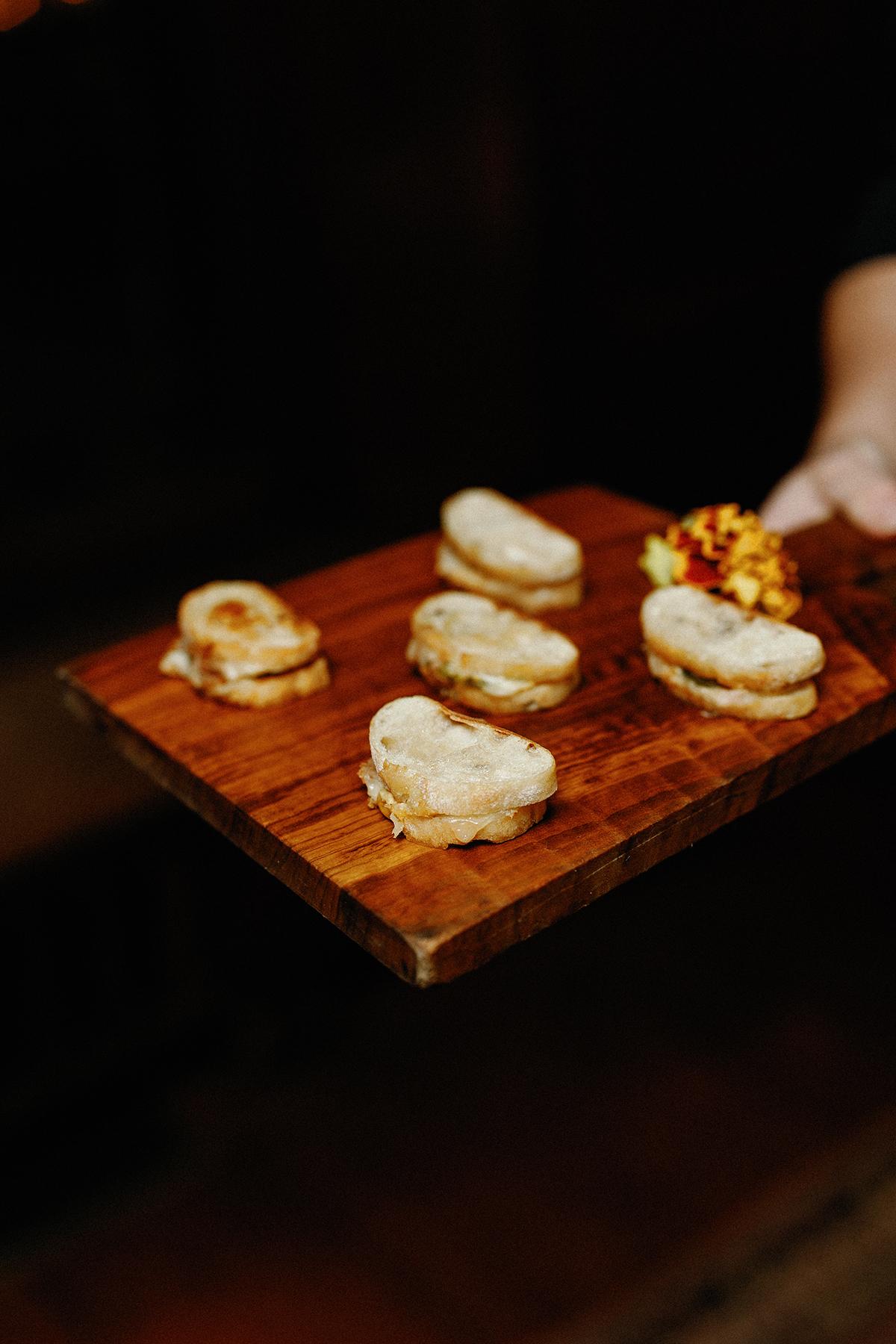 Canapés served on a wooden platter, garnished with edible flowers.