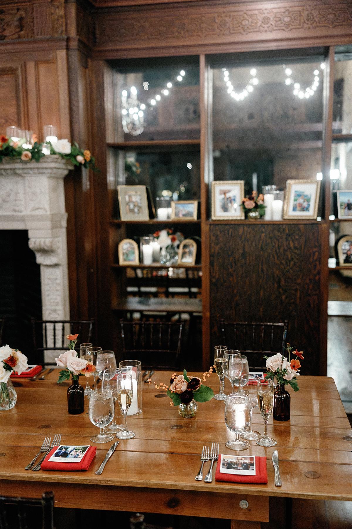 Elegant dining table with flowers, candles, and framed photos in a cozy room.
