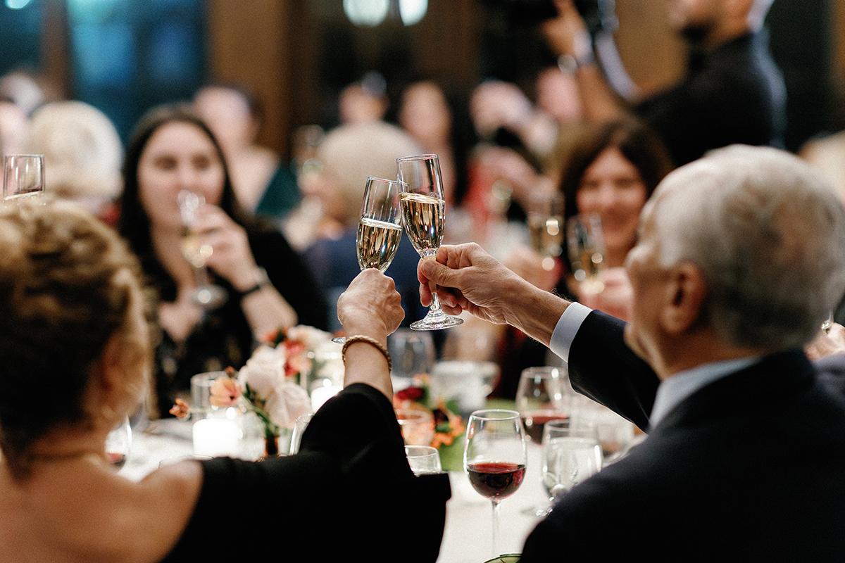 Guests toast with champagne glasses at a formal dinner event.