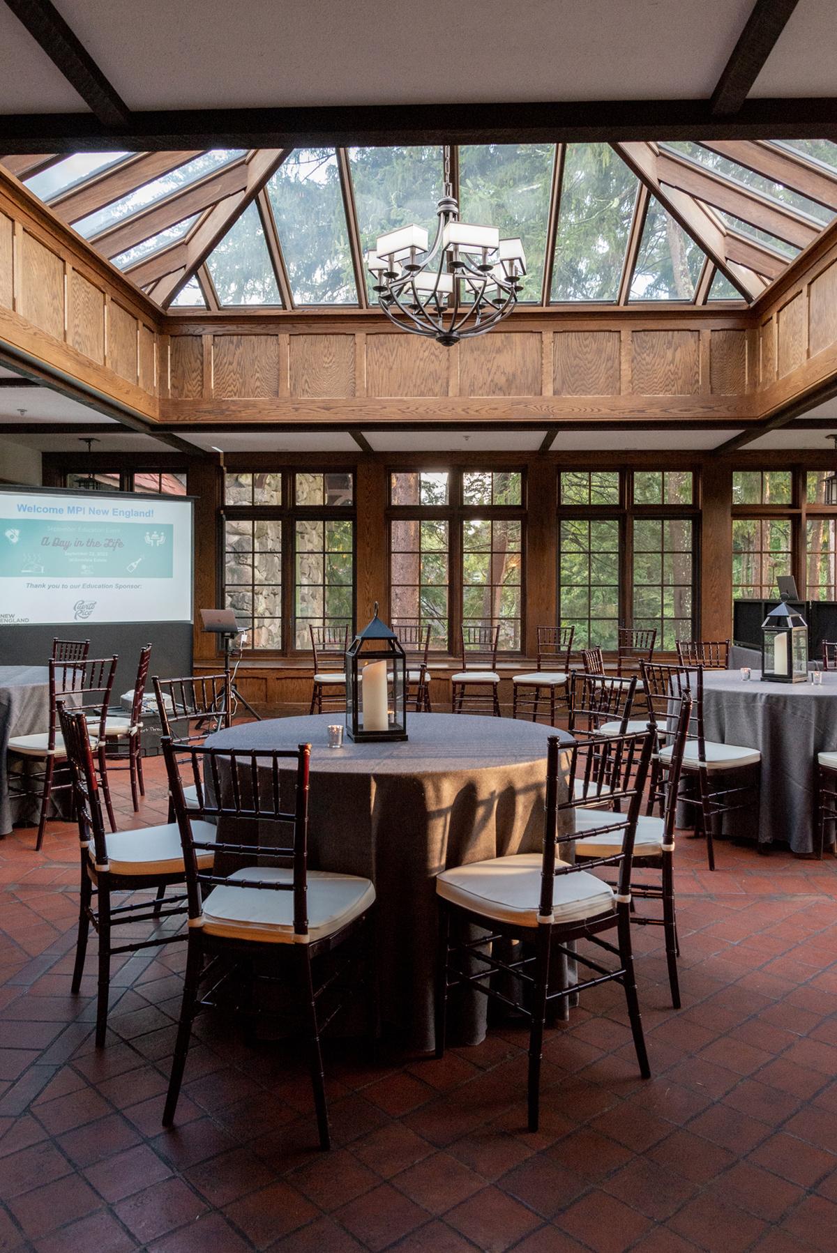 Elegant dining room with round tables, skylight, and chandelier.