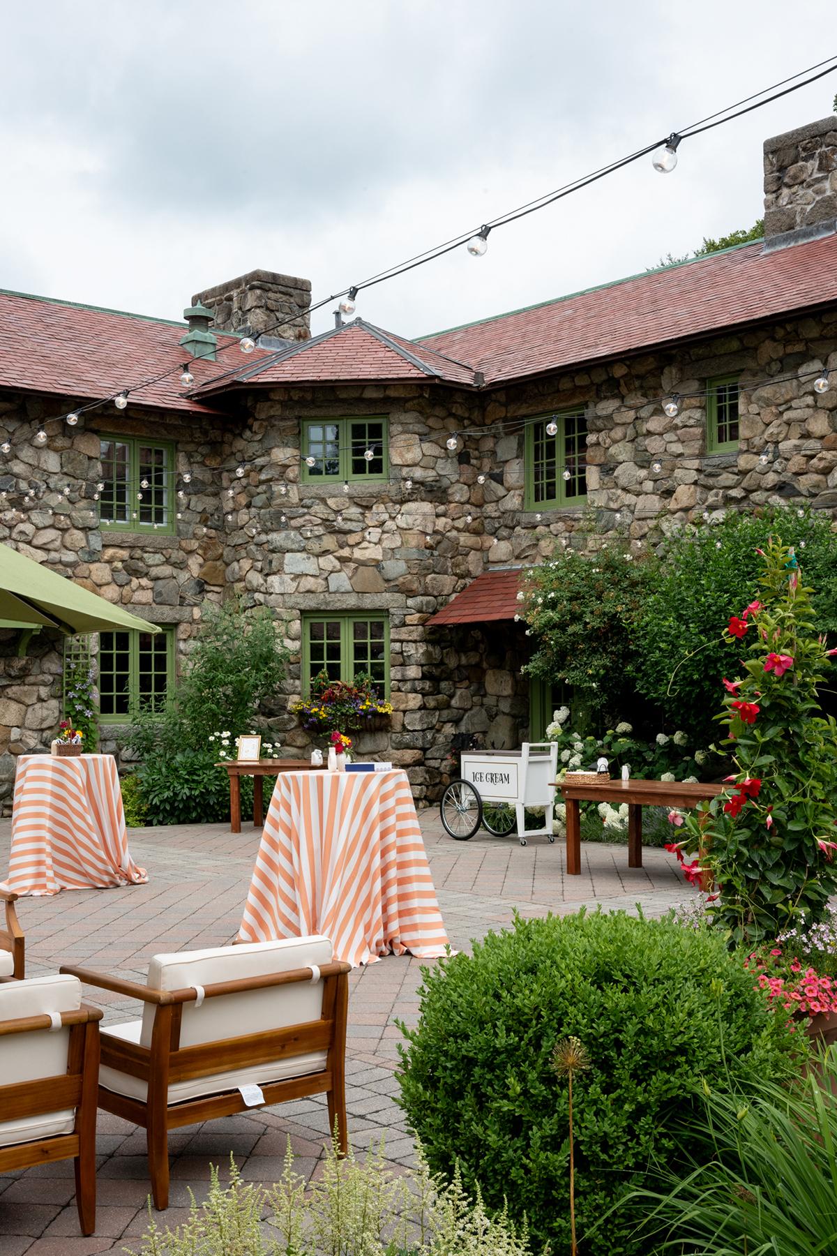 Historic stone building with patio tables and lounge chairs.