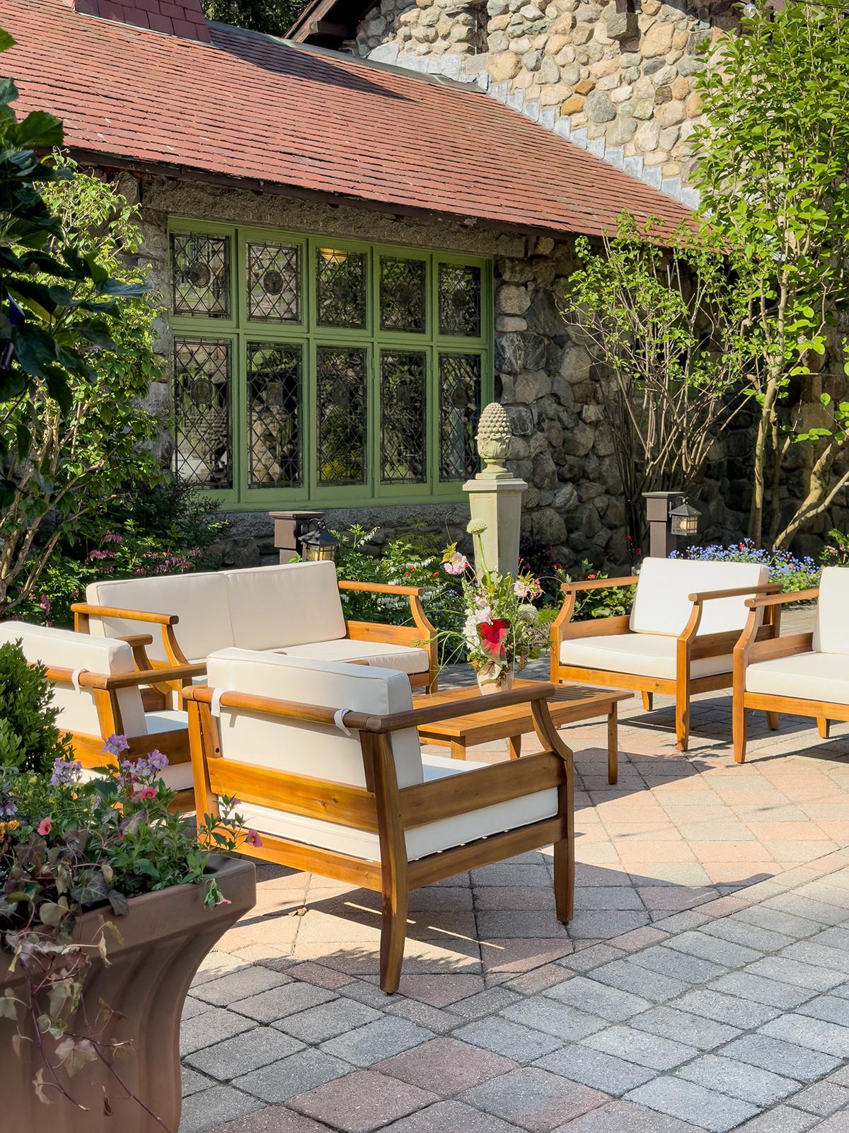 Outdoor patio with wooden chairs and stone building backdrop.
