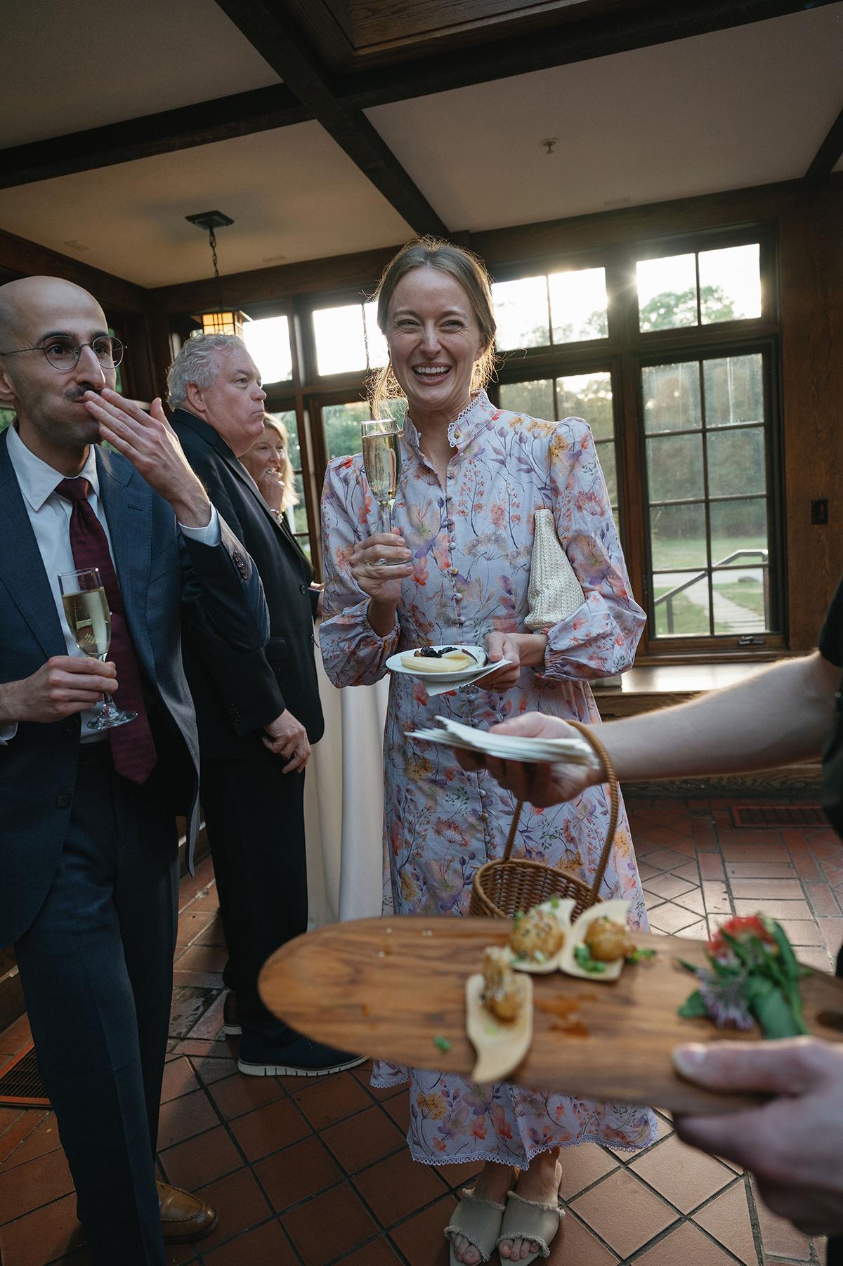 Guests at an indoor gathering, holding glasses and canapés.