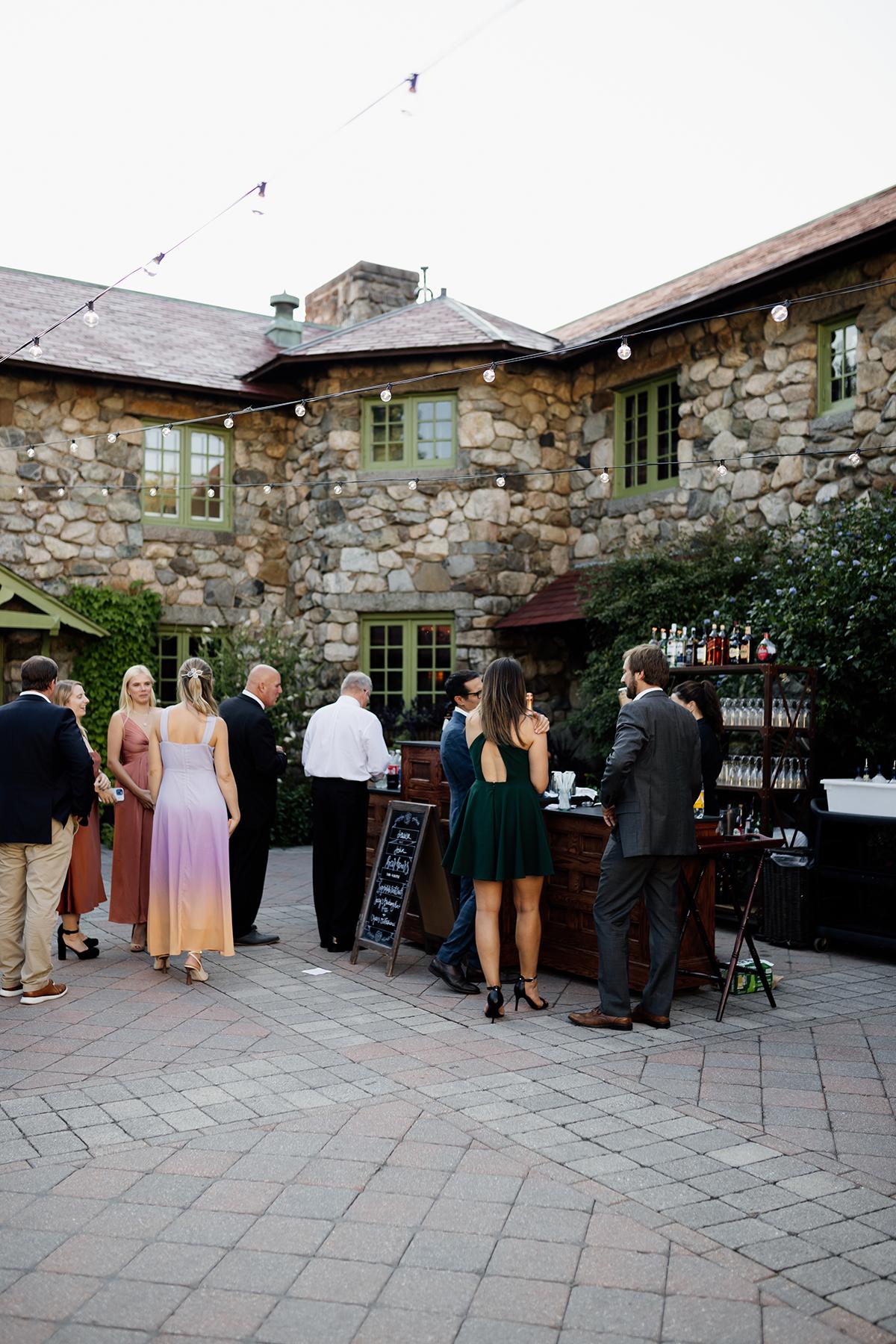 Courtyard gathering with people near a rustic stone building.