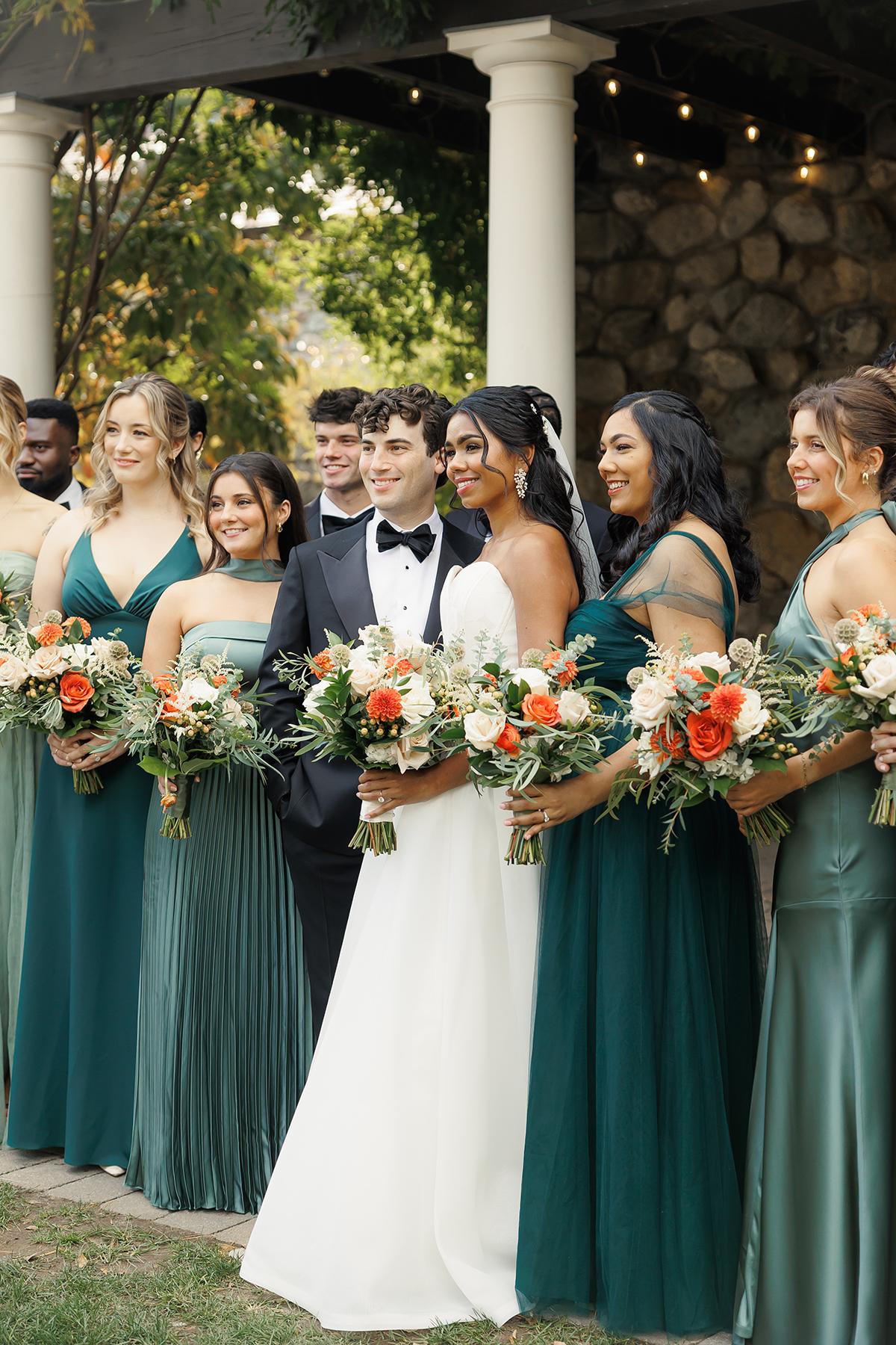 Wedding party with bridesmaids in teal dresses, groom in black, and bride in a white gown.