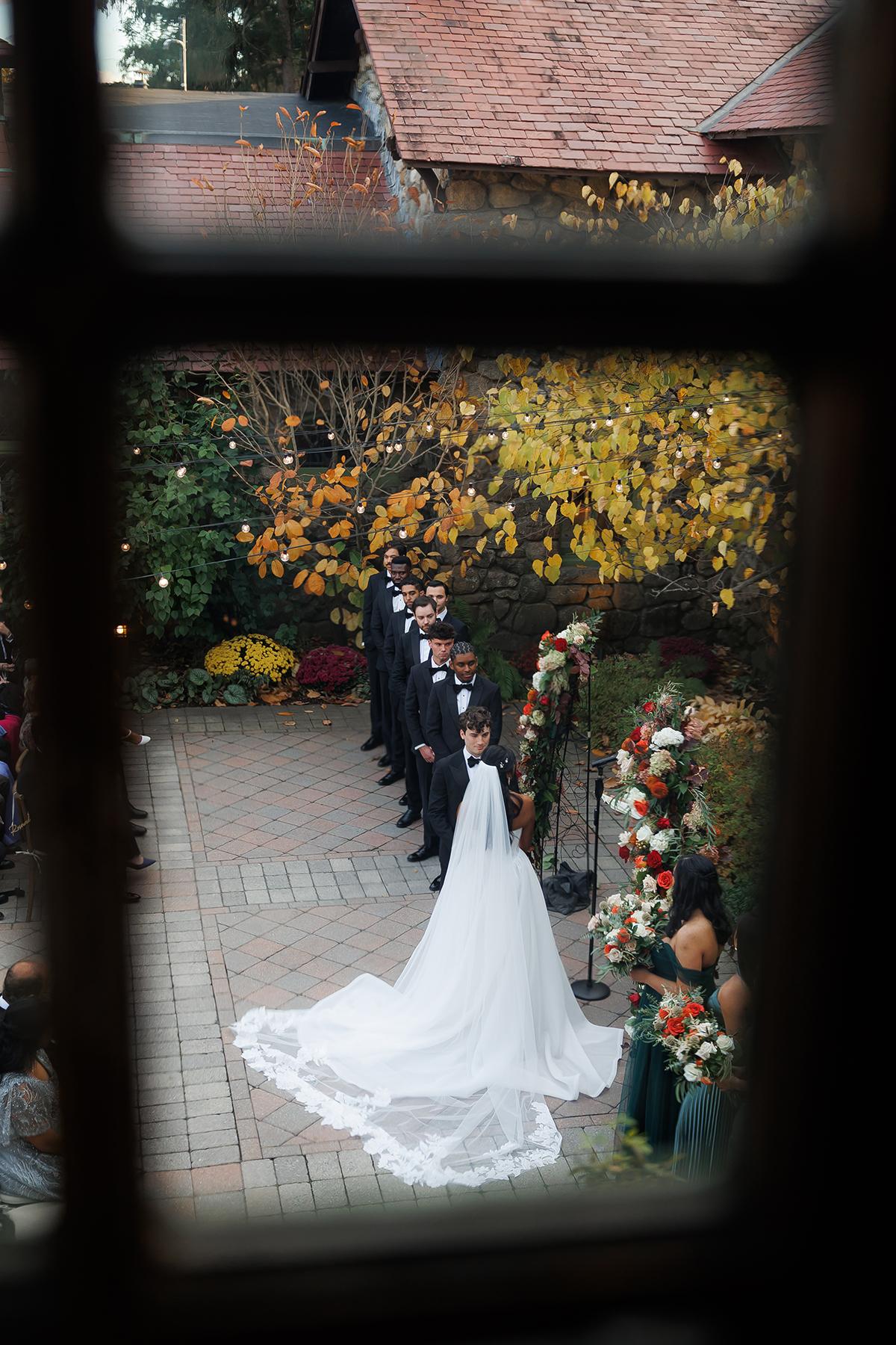 Bride and groom at outdoor wedding, surrounded by fall foliage.