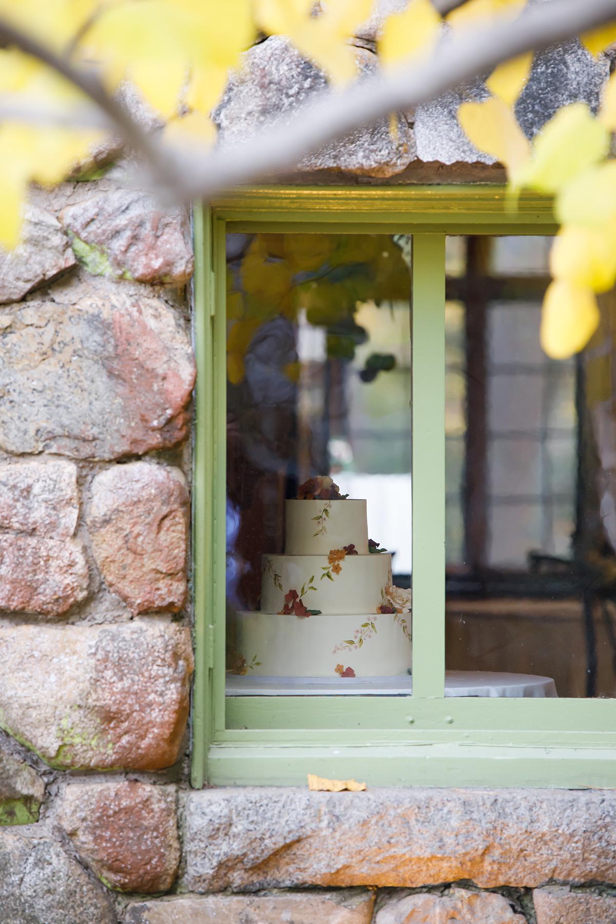 Cake with autumn leaves seen through a stone wall window.
