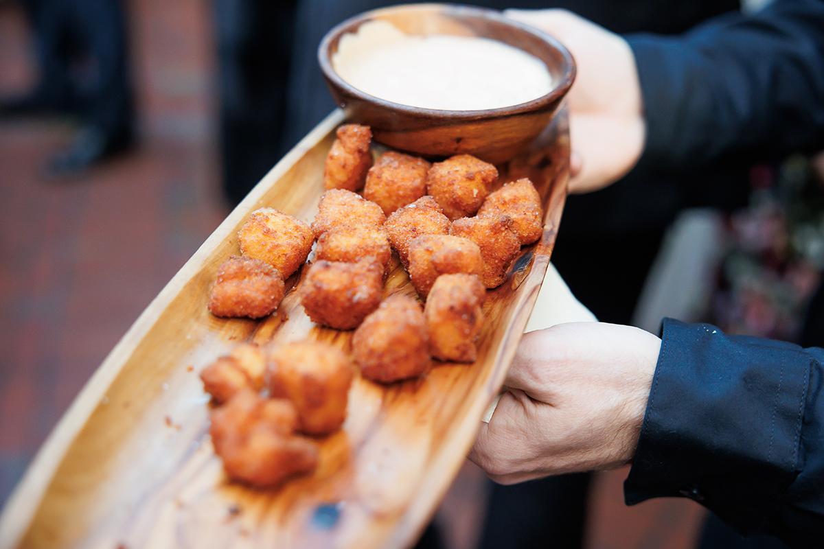 Fried appetizers on a wooden tray with dipping sauce.