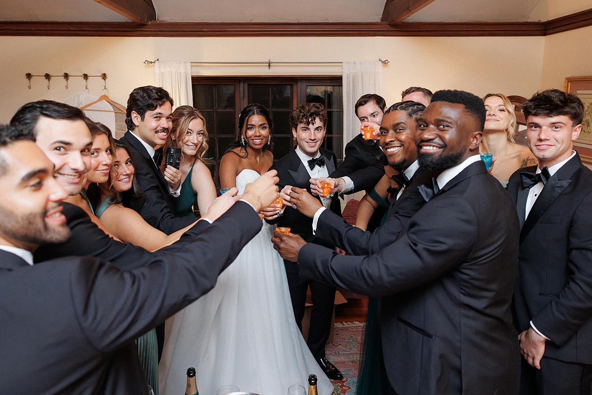 Guests in formal wear toast joyfully at a wedding reception.