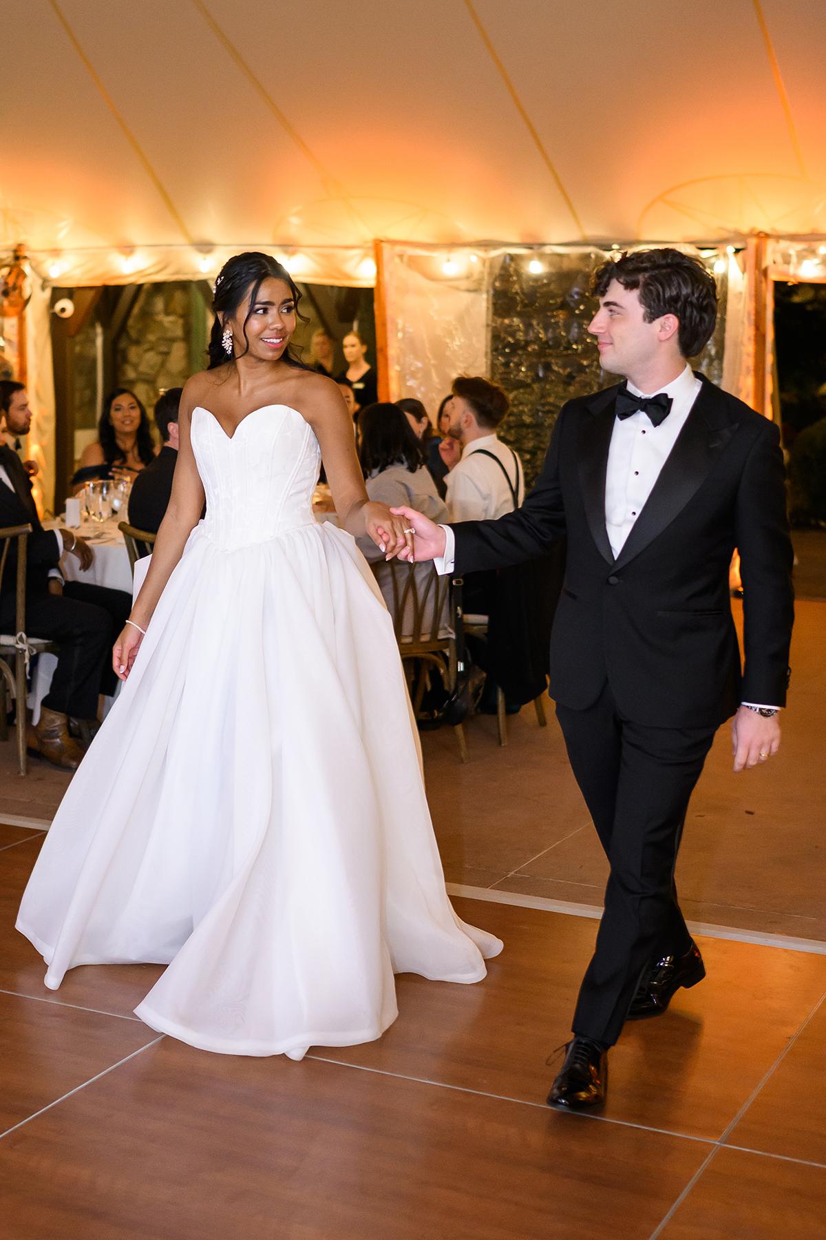 Bride and groom dancing at a wedding reception, smiling at each other.