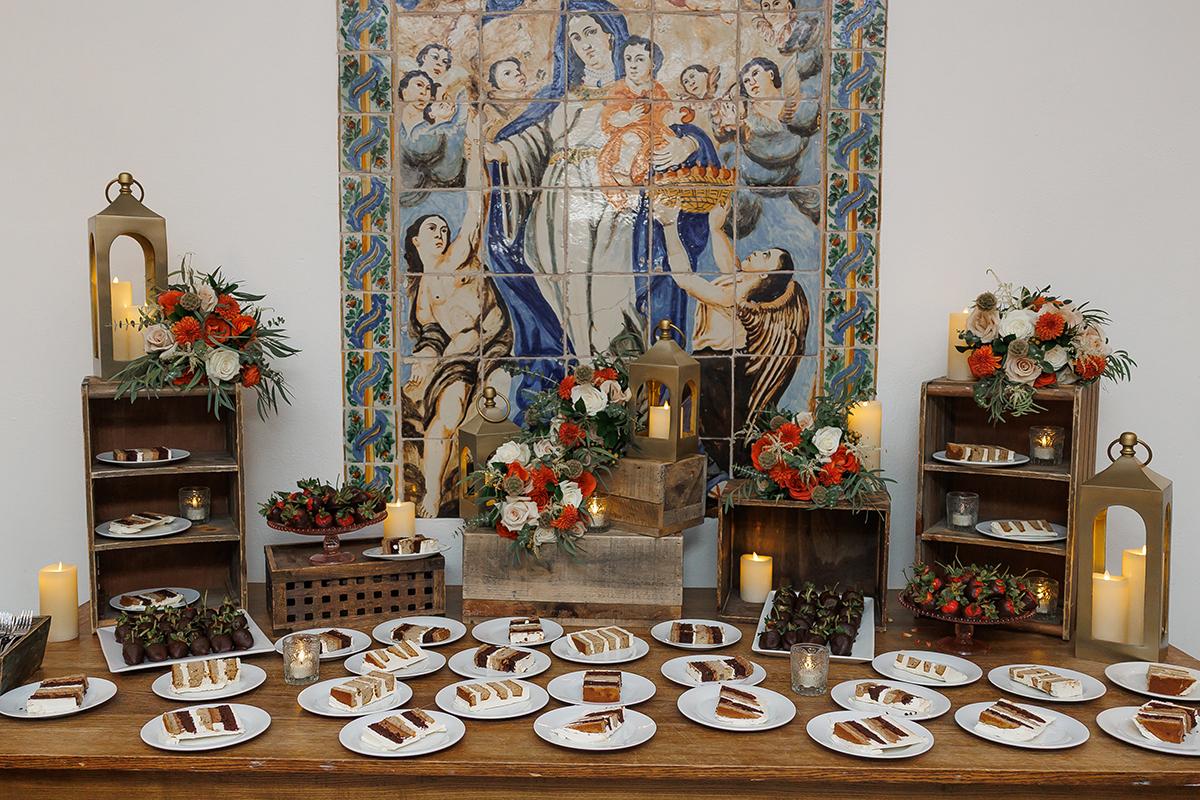 Dessert table with plates of pastries, decorated with candles and flowers.