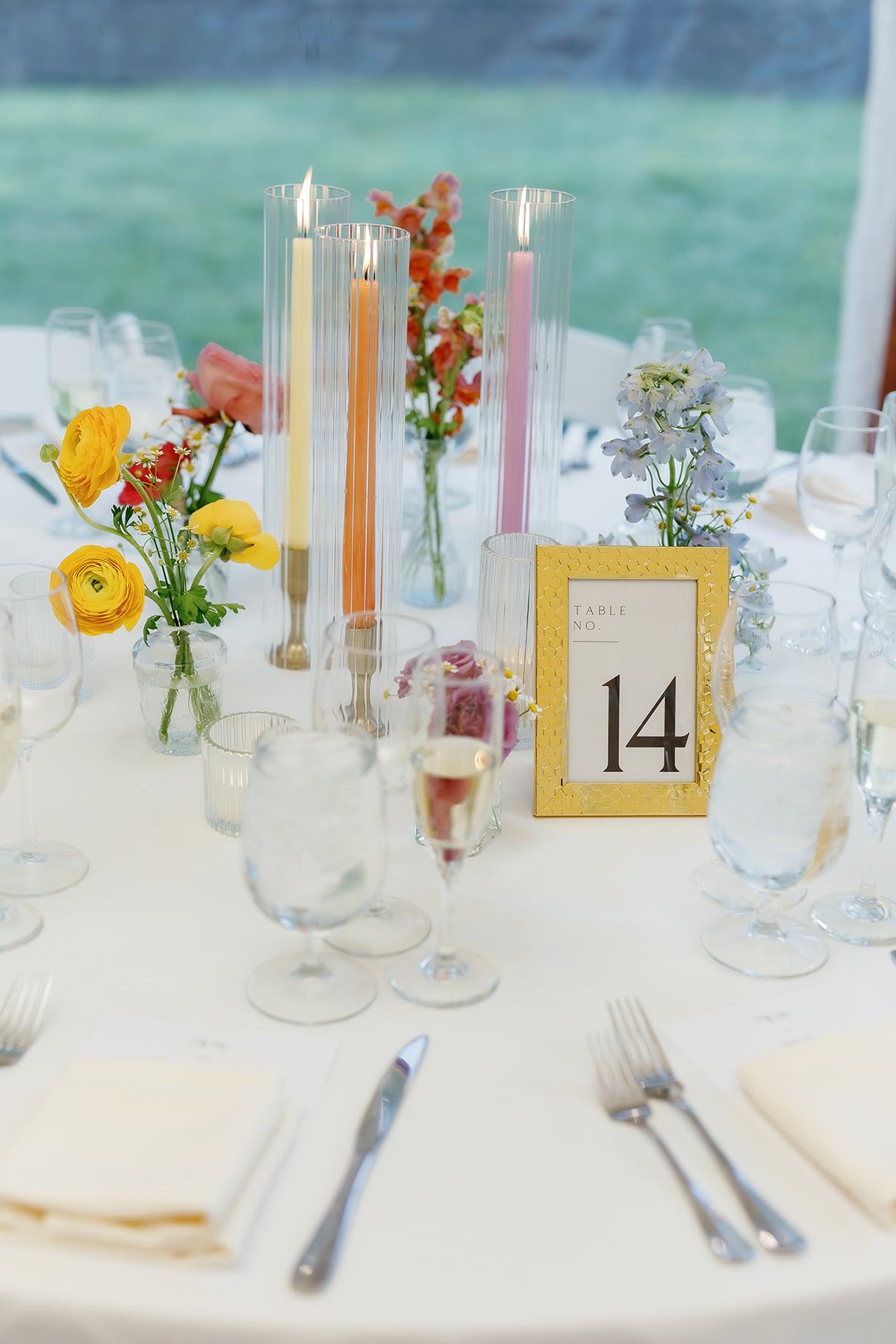 Elegant table setting with flowers, candles, and a table number 14 card.