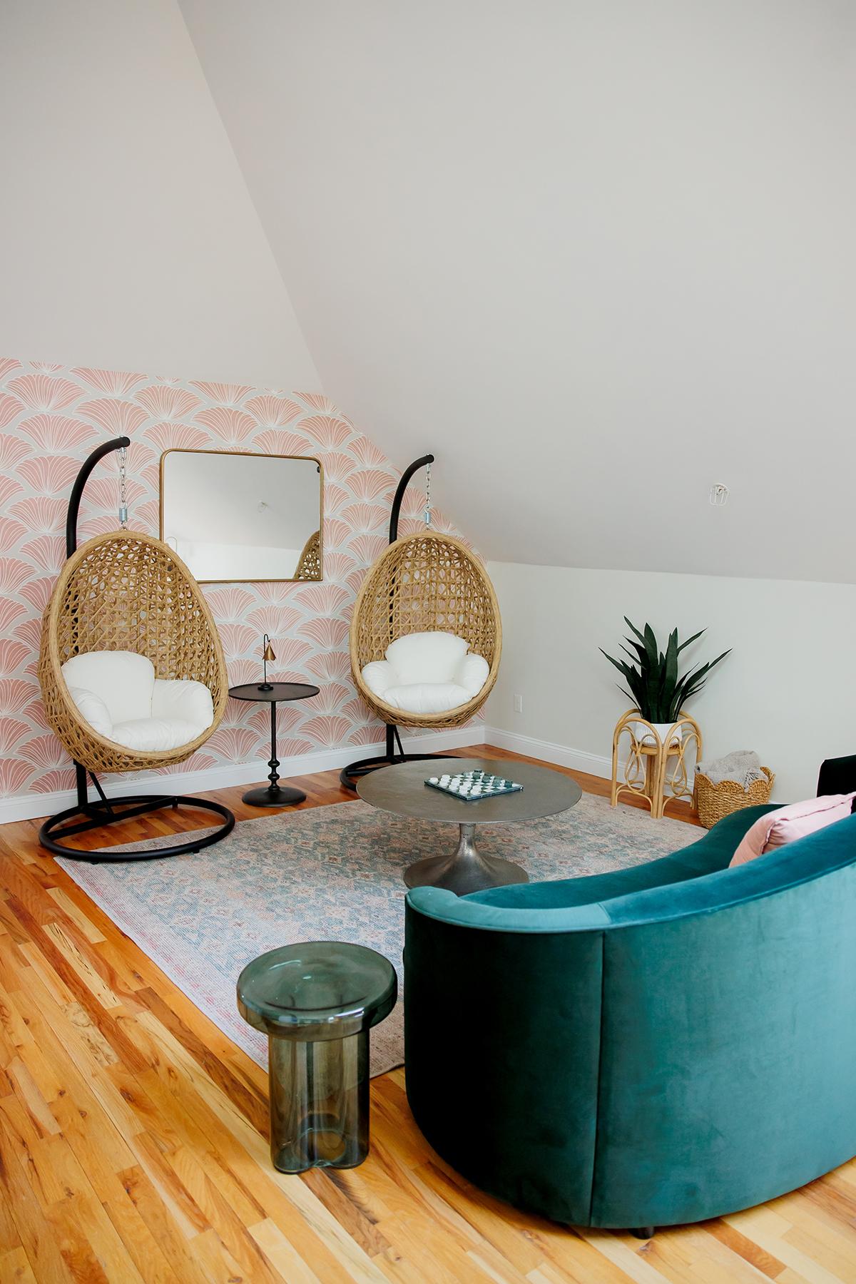 Cozy room with hanging wicker chairs, teal couch, and a plant.