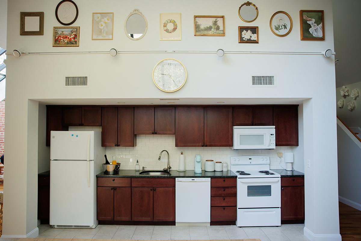 Kitchen with dark wood cabinets, white appliances, and framed art on walls.