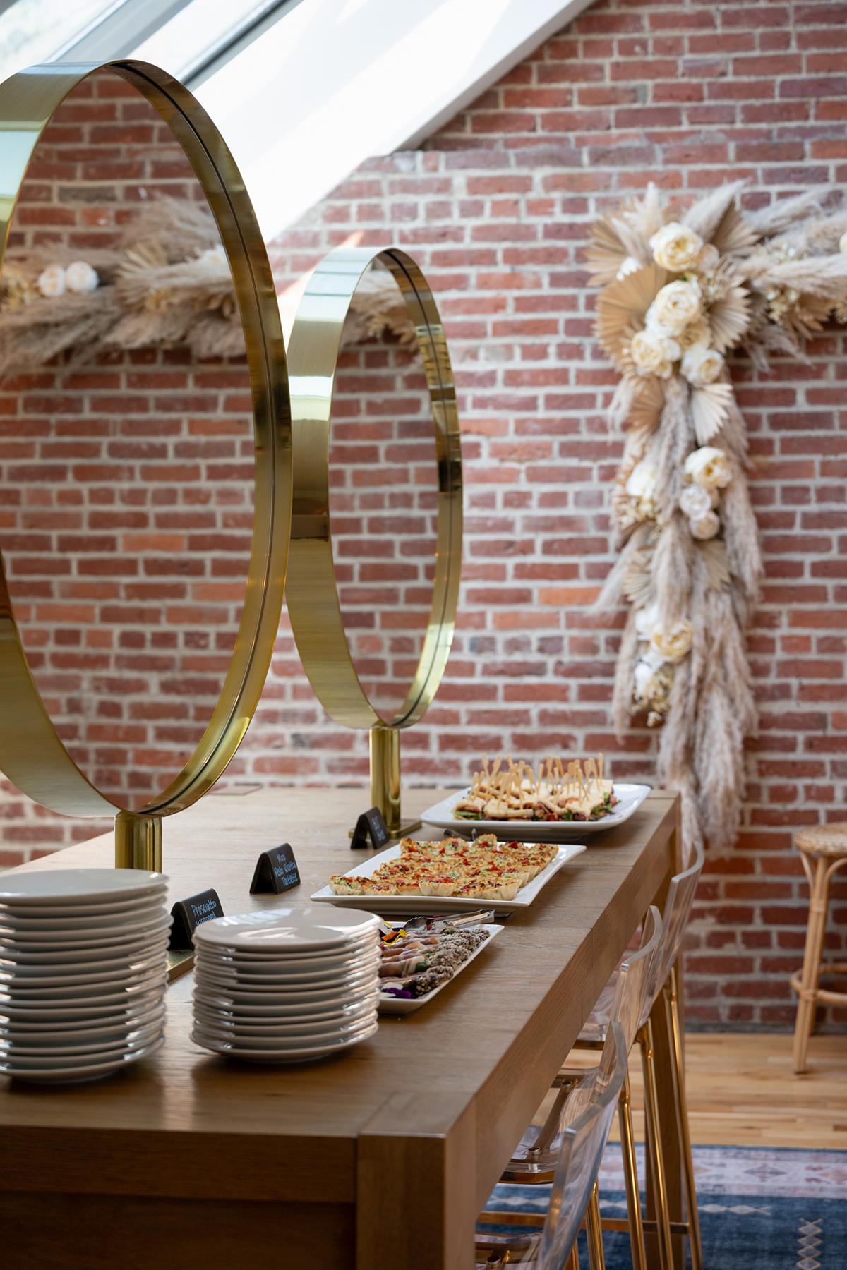 Elegant buffet setup with gold frames and brick wall backdrop.