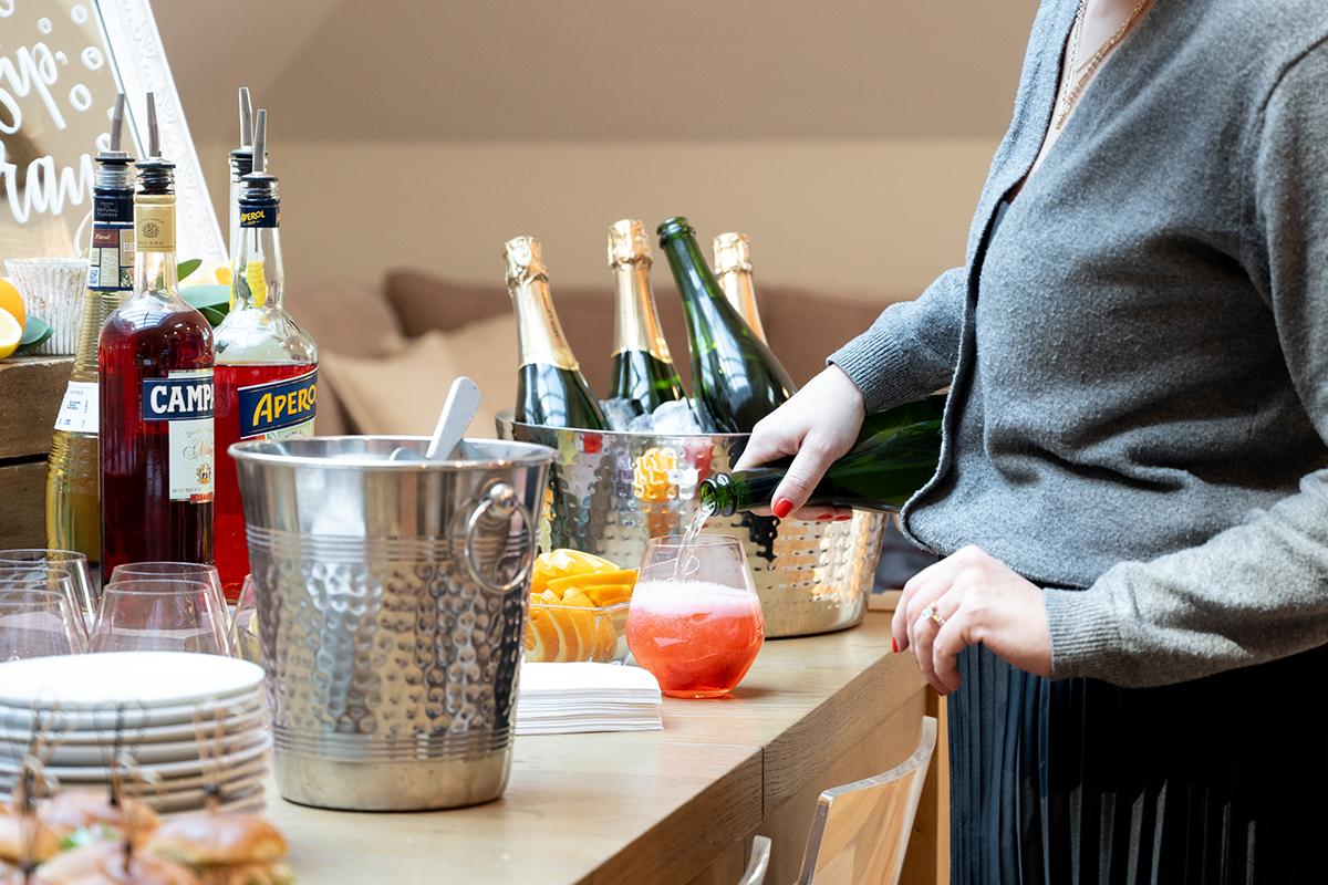 Person preparing drinks at a bar with bottles and ice bucket.